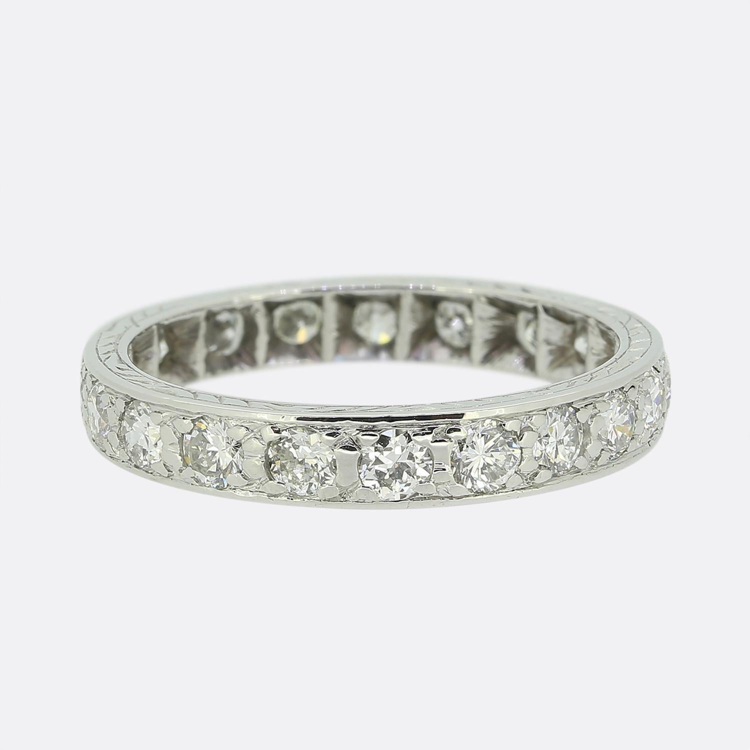 Here we have a stunning band ring adorned with a continuous row of round faceted natural diamonds. Each stone has been is expertly set in platinum, forming a seamless circle of sparkle. The piece is then made complete by neat engraving work at