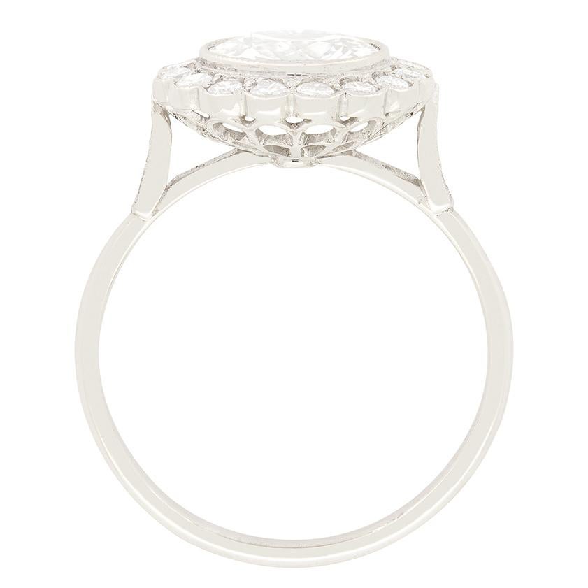 Un hermoso diamante de talla de transición de 1,60 quilates es el protagonista de este anillo en racimo fabricado en la década de 1950. El diamante engastado tiene un color H y una pureza SI2. Envolviendo la piedra central, se engastan otros
