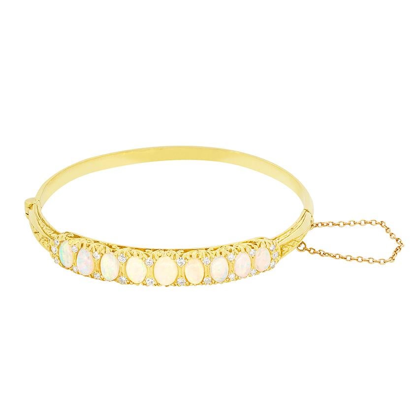 Este precioso brazalete, que data de la década de 1950, exhibe una colección de nueve ópalos etéreos. Engarzado en oro amarillo de 18 quilates, el ópalo central tiene un peso de 0,25 quilates, y cada piedra se va estrechando hasta llegar a la más