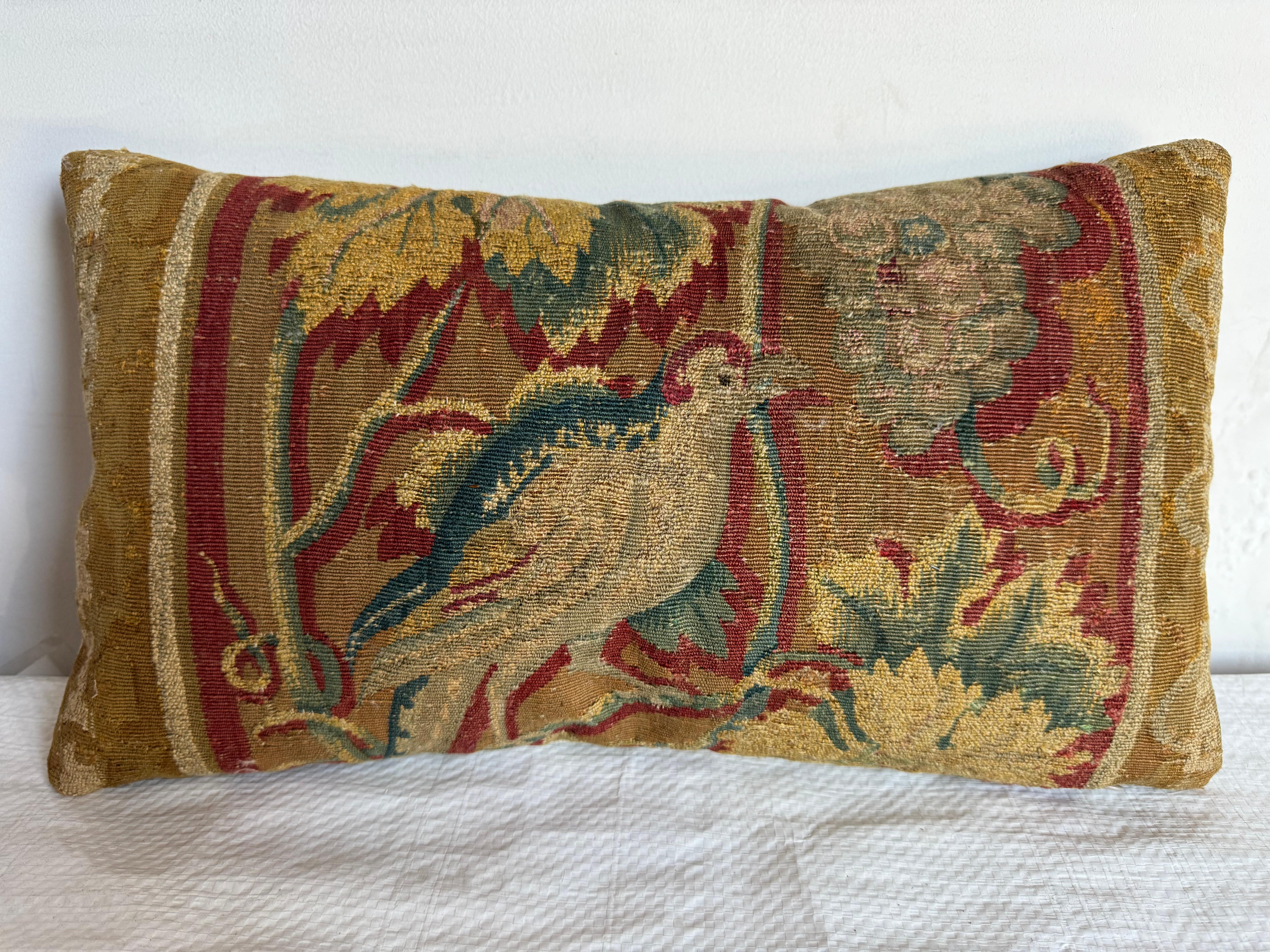 Immergez votre espace dans un charme royal avec ce coussin en tapisserie bruxelloise du XVIe siècle, orné d'opulents motifs de fruits et de feuillages. Les verts et les dorés de la terre confèrent une esthétique chaleureuse et