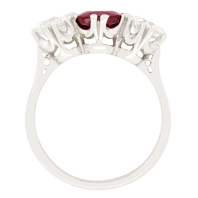 This marvellous trilogy ring features an impressive 1.70 carat central ruby, flanked by a pair of round brilliant diamonds. Sitting proudly, the central blood red Ruby is a cushion cut stone, completely natural and unheated. Complementing the ruby