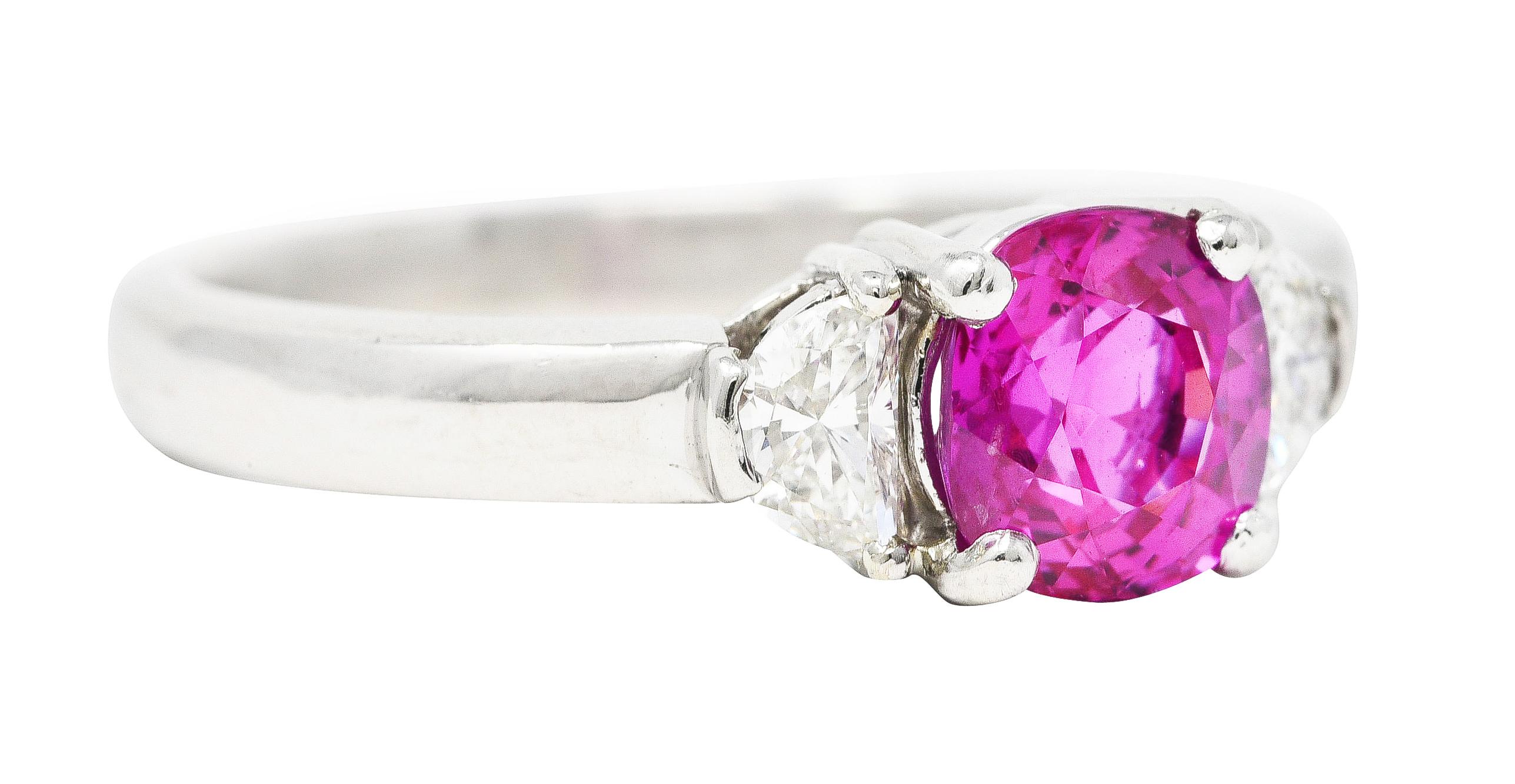 Featuring a cushion cut sapphire weighing approximately 1.53 carats. Transparent, vividly pink in color, with uniformly medium saturation. Basket set and flanked by half-moon cut diamonds. Weighing collectively approximately 0.25 carat - G/H color