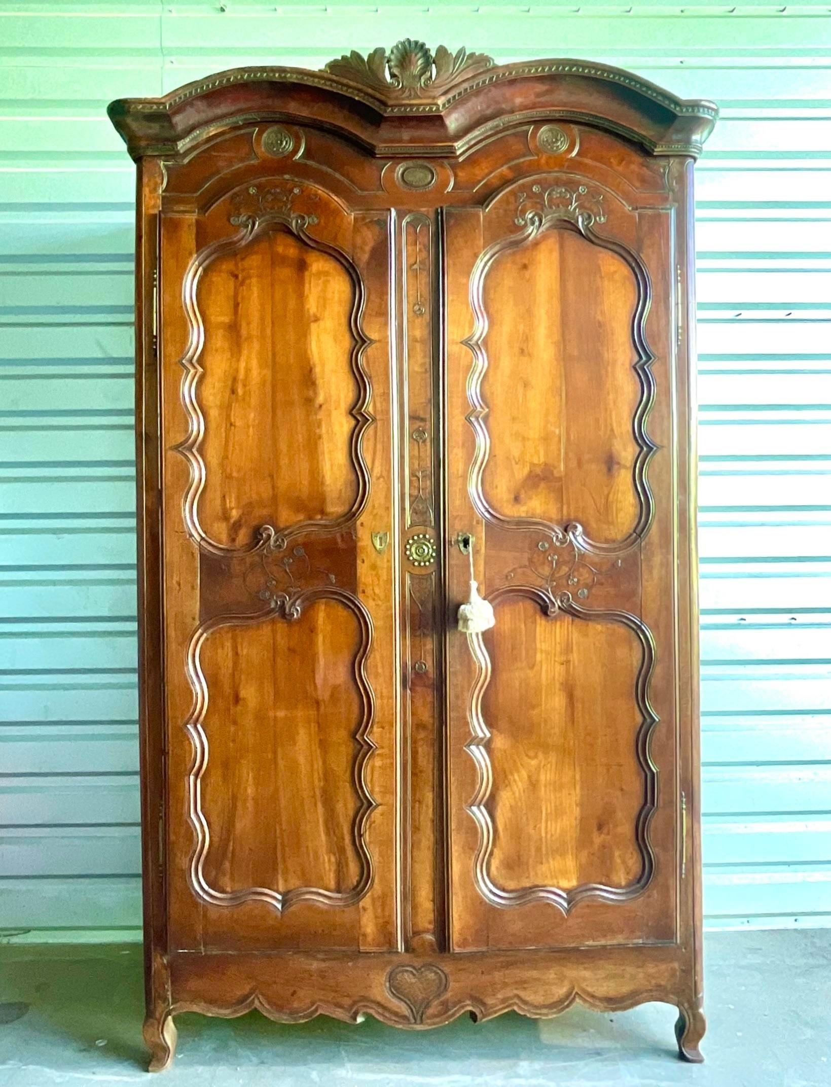 A fabulous vintage Boho armoire. Incredible hand carved detail in a solid chestnut case. Made in 1780 and a beautiful warm patina from time. Working key included. Currently open panel in back, but easily changed. Acquired from a Palm Beach estate.