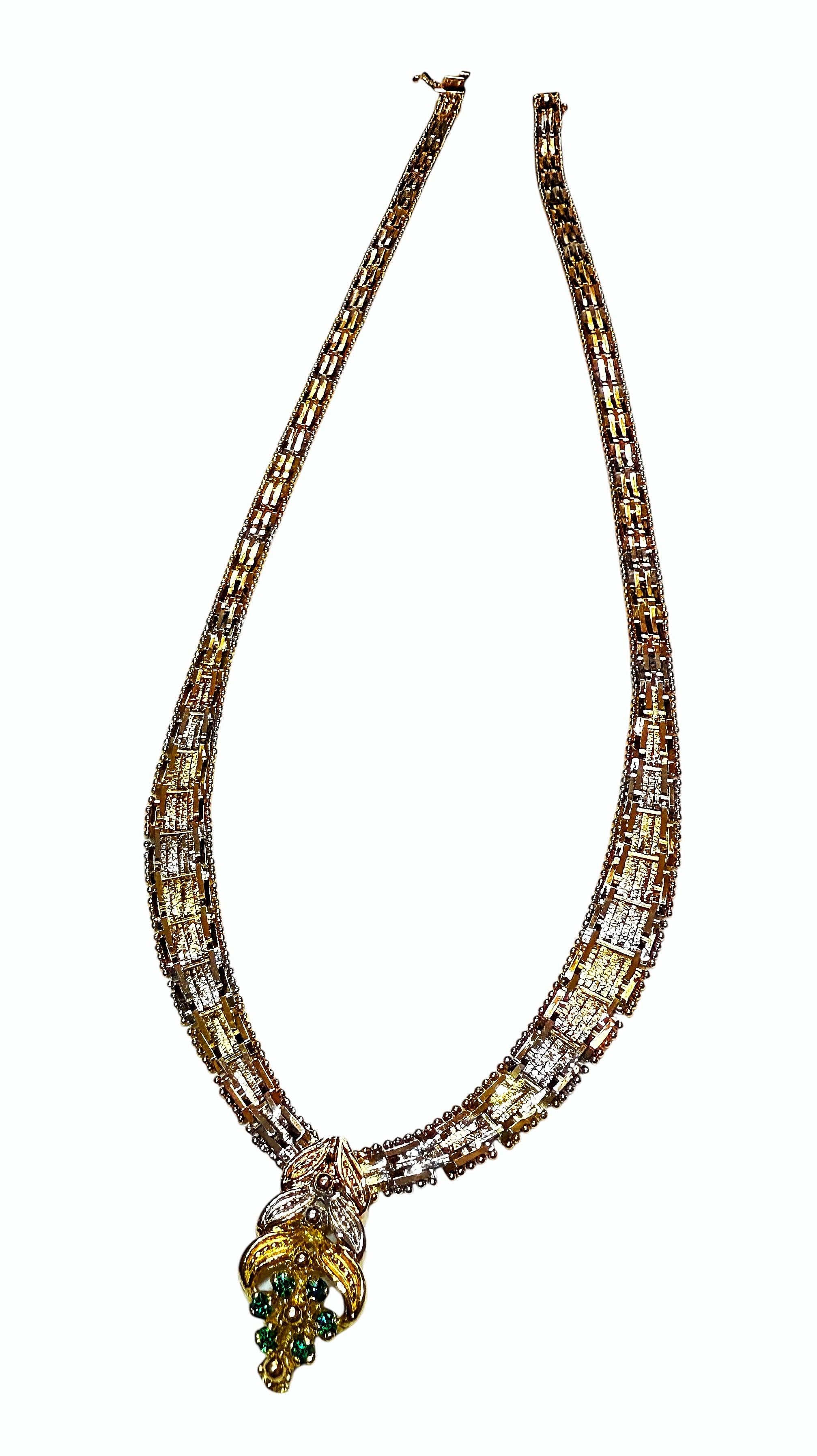 The chevron symbolizes wealth and status.  This necklace has graduating rectangular links in silver, gold and rose gold color that culminate in an elegant V piece. This piece has a 3-tone tier design with 6 round emeralds at the base.  The emeralds