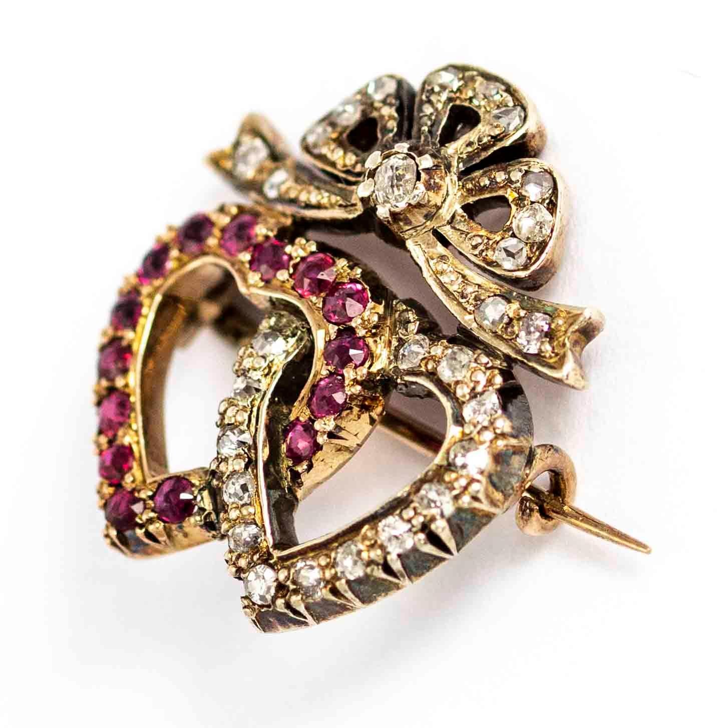 A superb vintage brooch featuring a pair of linked hearts below a bow motif. One of the hearts is set with wonderful pink topaz, the other is set with white diamonds. The bow if further set with diamonds, with the largest stone in the knot of the