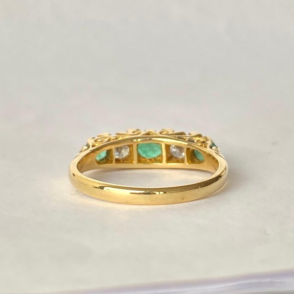 An exquisite vintage five-stone ring set with beautiful alternating emeralds and diamonds. The superb central round-cut emerald measures approximate 40 points. Either side of this are two wonderful brilliant-cut white diamonds measuring