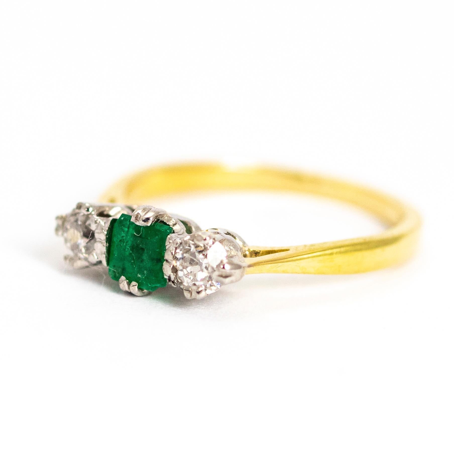 A beautiful vintage three-stone ring, centrally set with a superb square-cut green emerald flanked by two lovely white diamonds measuring approximately 18 points each.  The stones fixed in white gold settings to complement their wonderful colour.