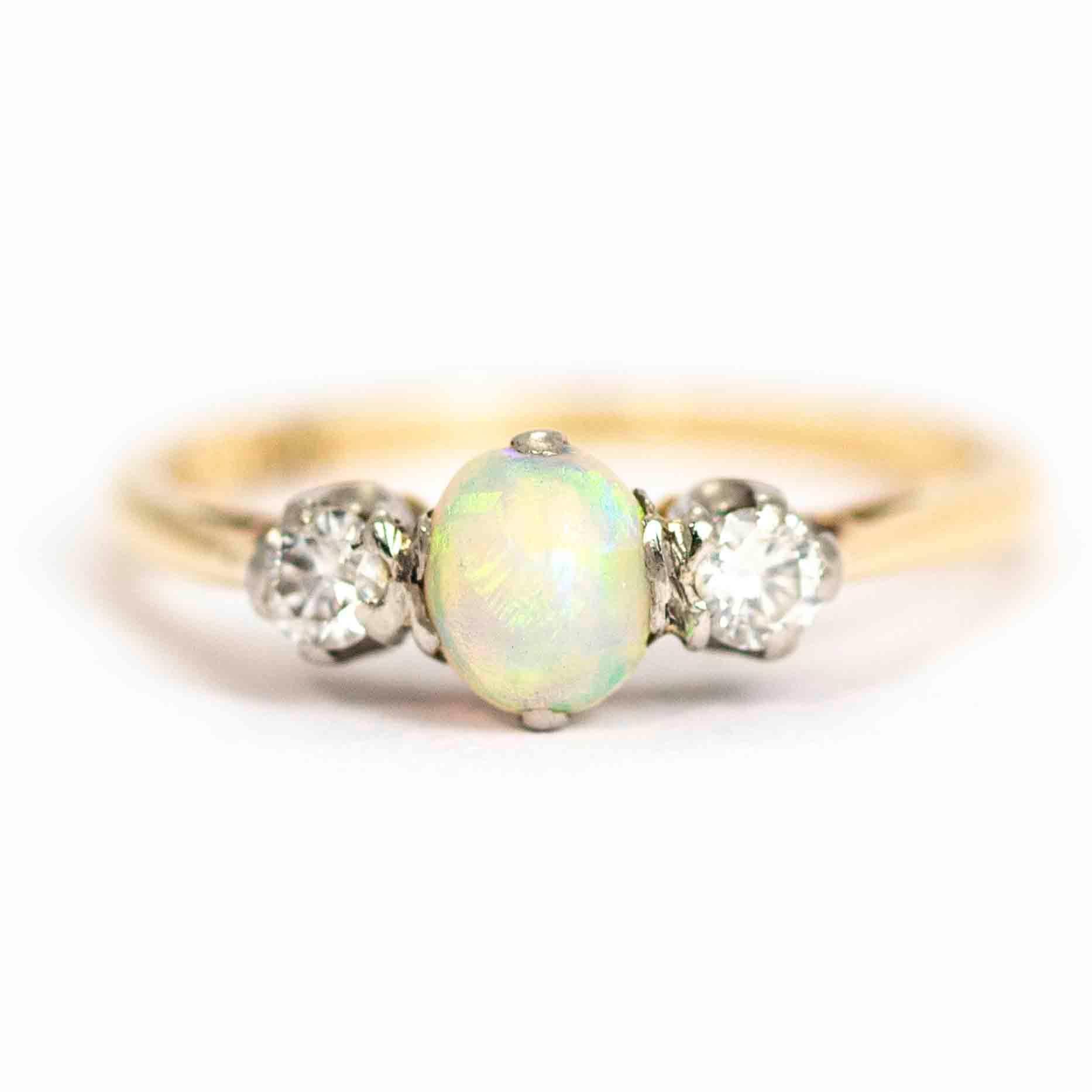 A wonderful vintage ring three-stone ring. The central cabochon cut opal has stunning colour, flanked by two round cut white diamonds measuring approximately 9 points each. The stones are set in platinum and the band is modelled in 18 carat yellow