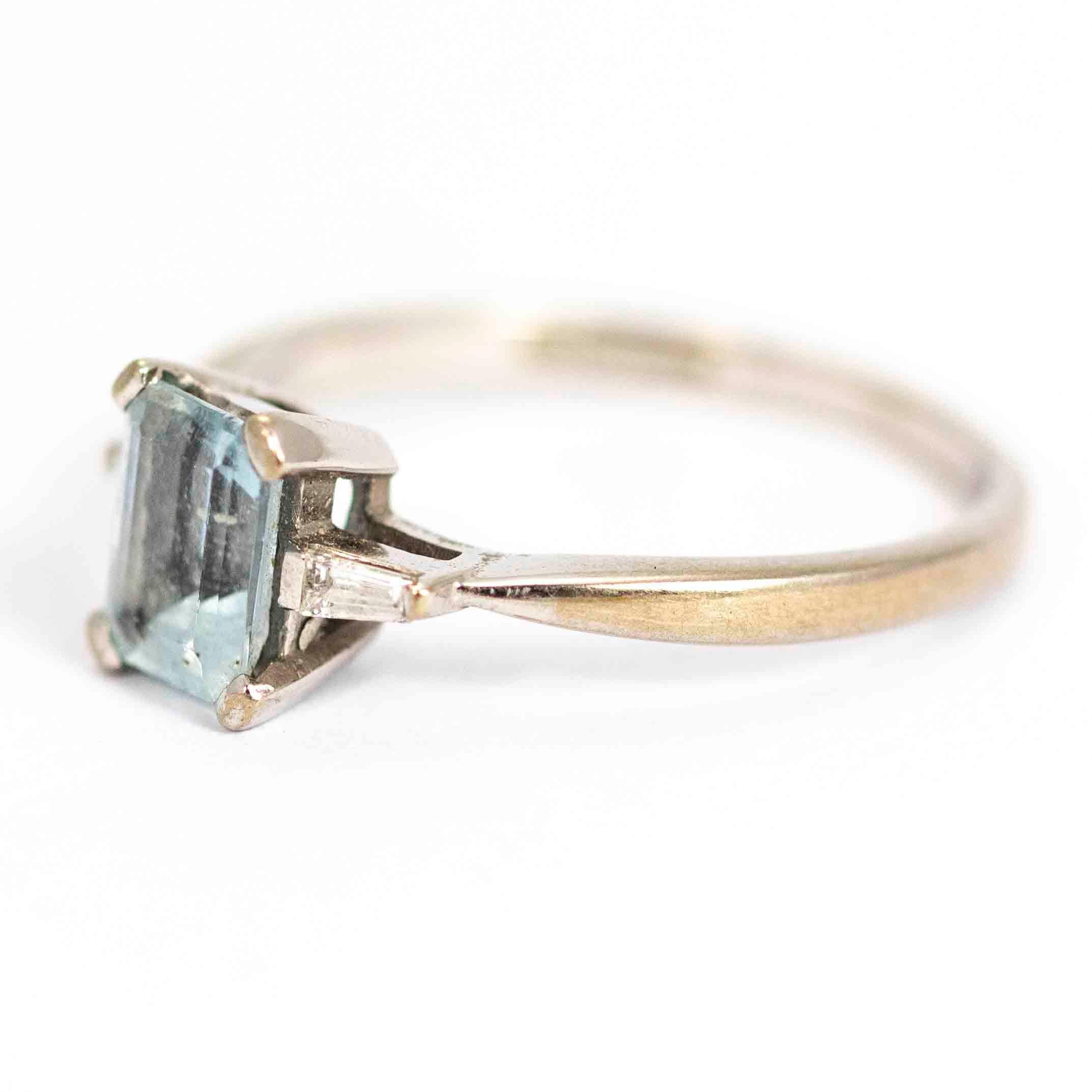 An exquisite vintage ring centrally set with a stunning emerald cut aquamarine measuring approximately 1 carat. Elegantly flanking the aquamarine are two beautiful baguette cut diamonds. Modelled in 18 carat yellow gold. Hallmarked Birmingham,