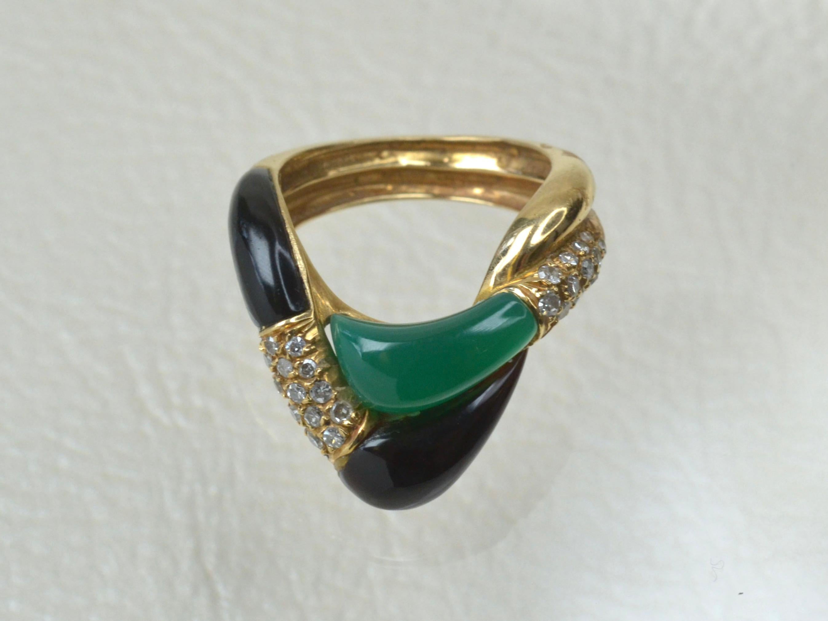 Dieses ineinander greifende Design aus den 1970er Jahren besteht aus zwei glatten Stücken Blanko-Onyx und einem glatten, geschliffenen Stück leuchtend grüner Jade. Insgesamt 26 weiße Diamanten unterstreichen die tiefen Farben. 
Der Ring hat ein