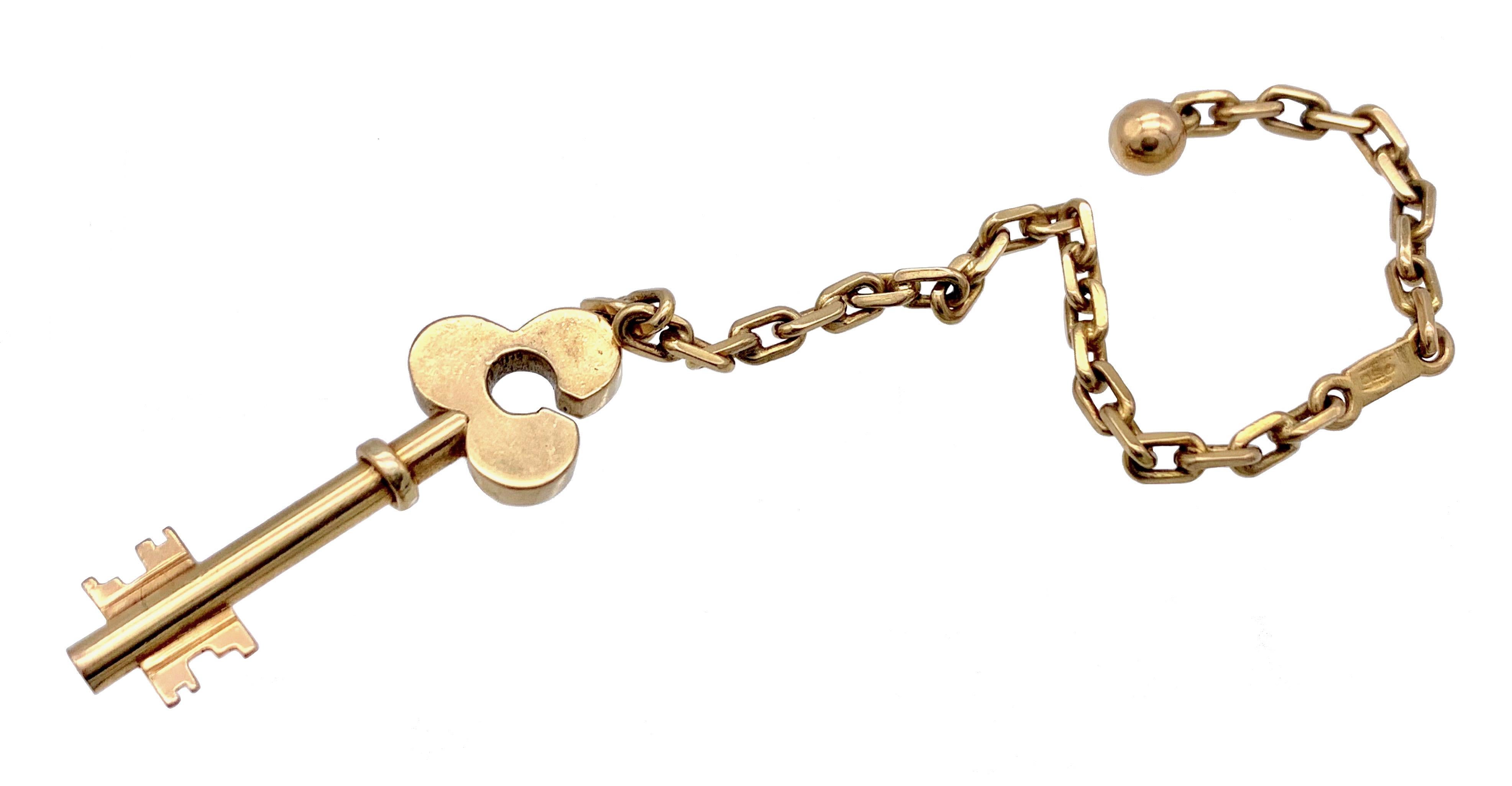 Dieser amüsante Schlüsselanhänger in Form eines Schlüssels, der an einer goldenen Kette befestigt ist, ist mit einer goldenen Kugel versehen, die die Kette im Schlüsselkopf fixiert.