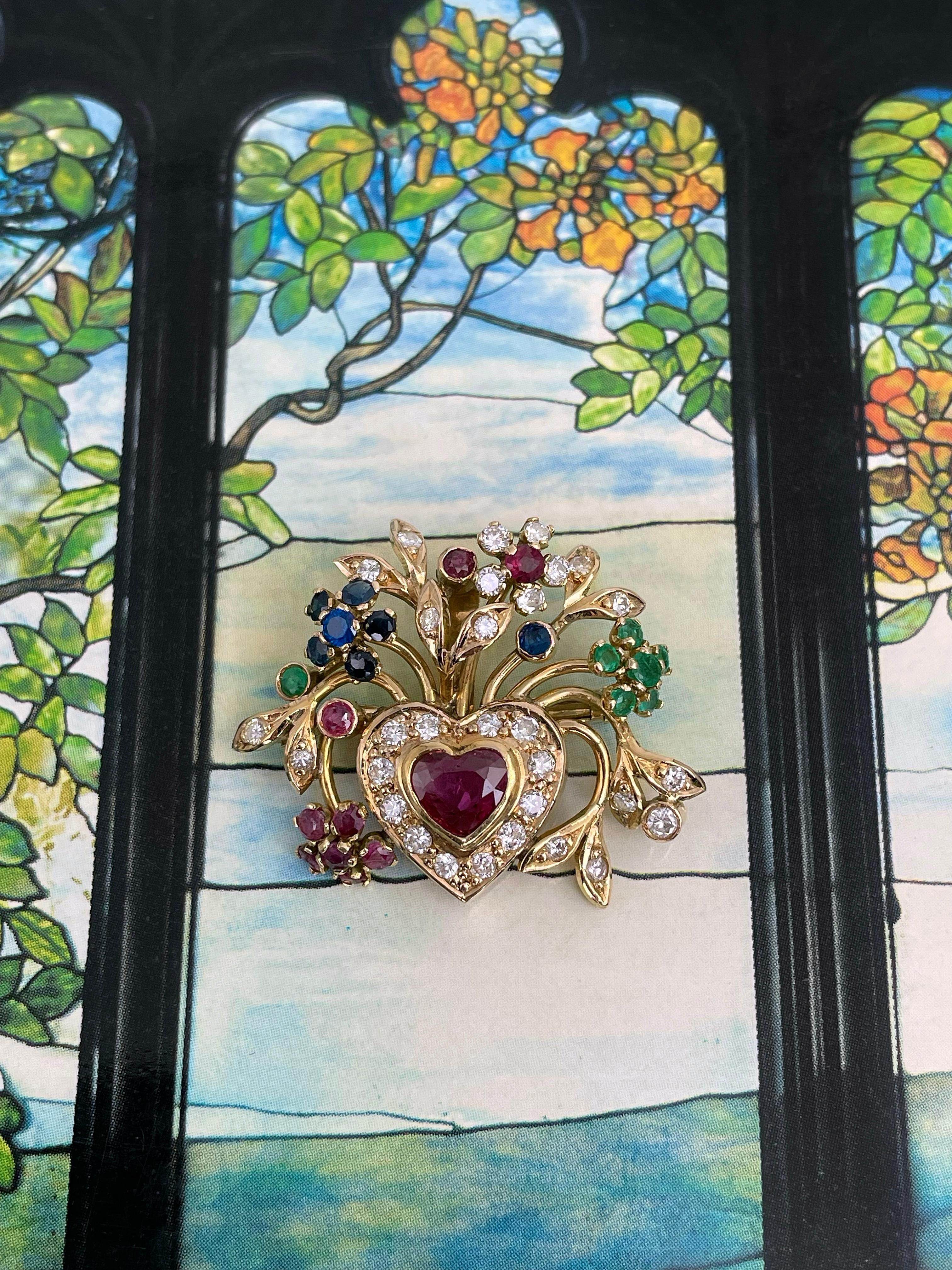 This is a lovely mid century floral design heart pendant brooch crafted in 18K yellow gold. Circa 1950. It features diamonds, rubies, emeralds, sapphires. 

Can be worn as a pendant or a brooch. Has a safe trombone clasp. 

Size: 3x2.5cm
Weight: