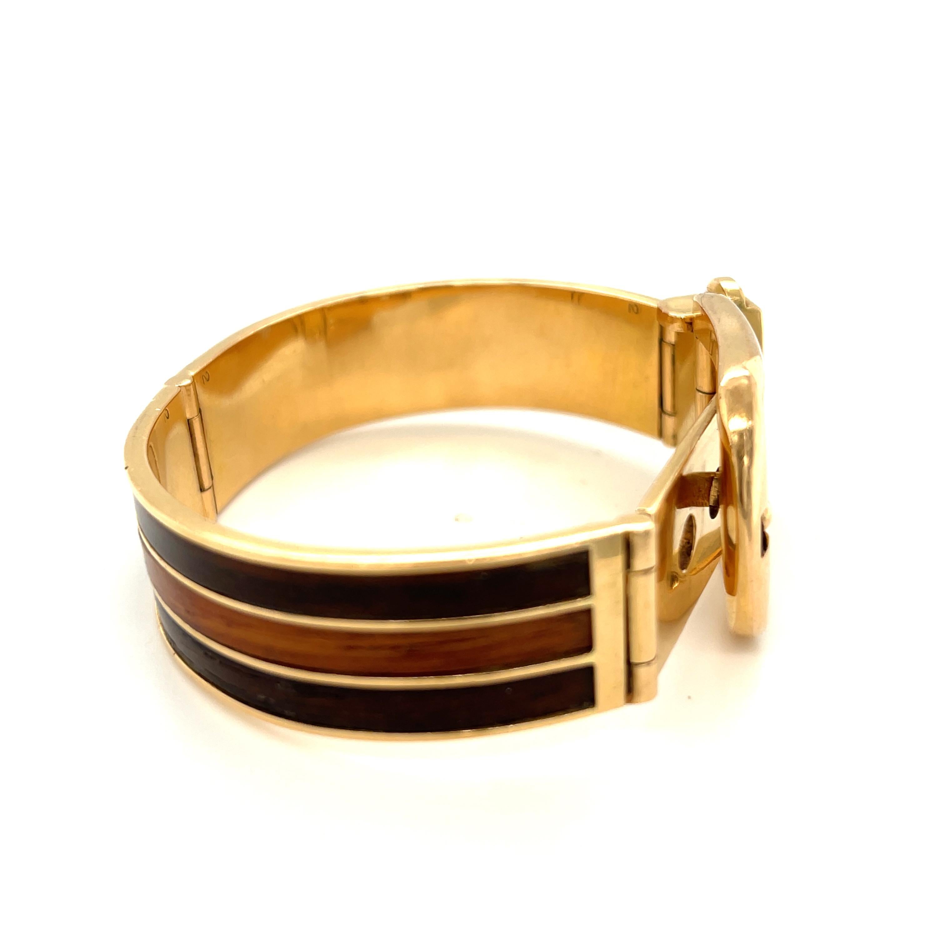 An iconic vintage 18k yellow gold and wood buckle bracelet by Gucci. This bracelet was likely made in the 1970s. The bracelet cleverly opens like a buckle and has two stations. The bracelet is iconic of Gucci’s bold hardware and aesthetic. The wood