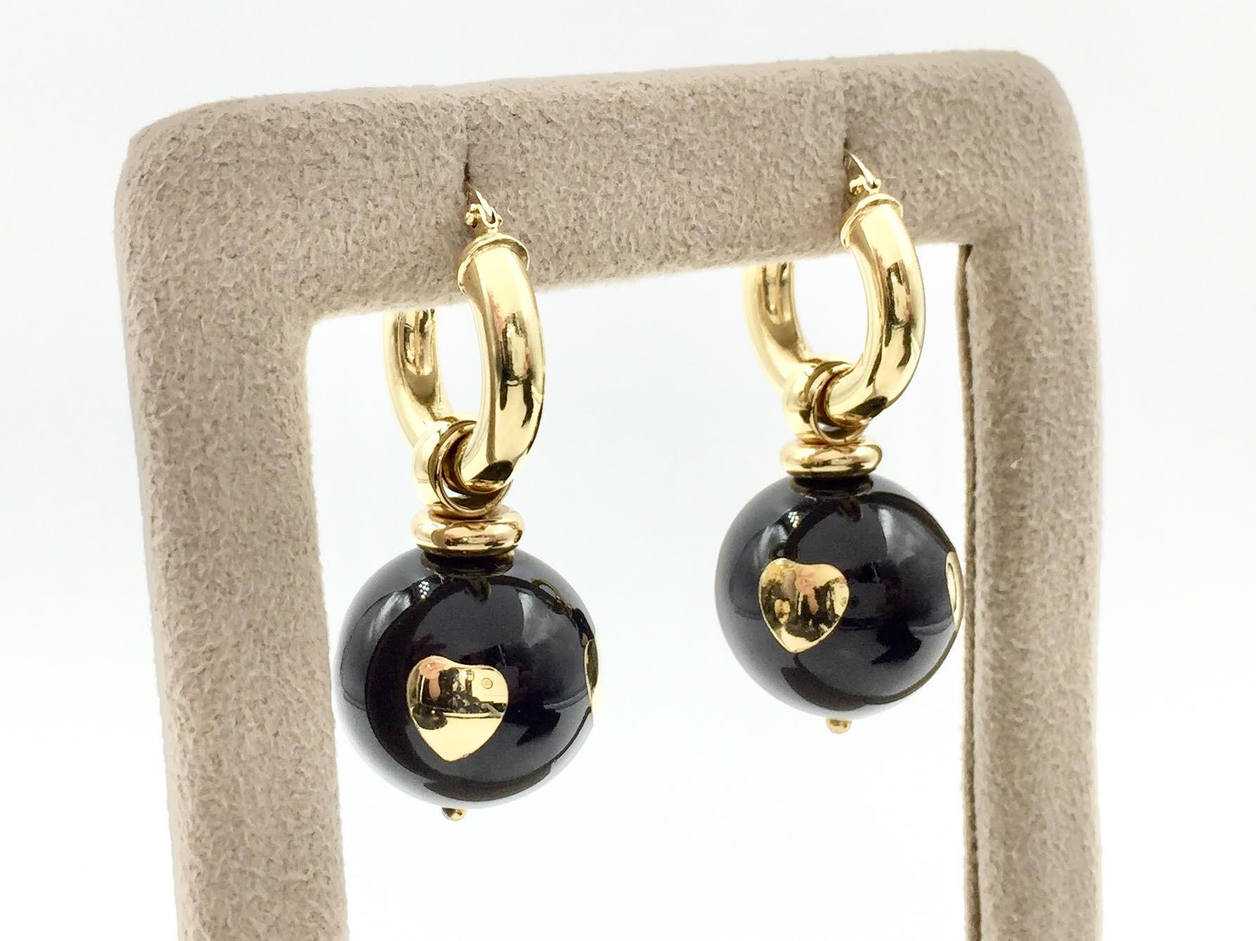 Made with high shine, polished 18k yellow gold. The 18mm round black enamel ball hangs securely from a wide hoop earring. The polished black enamel features four polished gold hearts. Earrings are light weight, comfortable enough for every day wear.