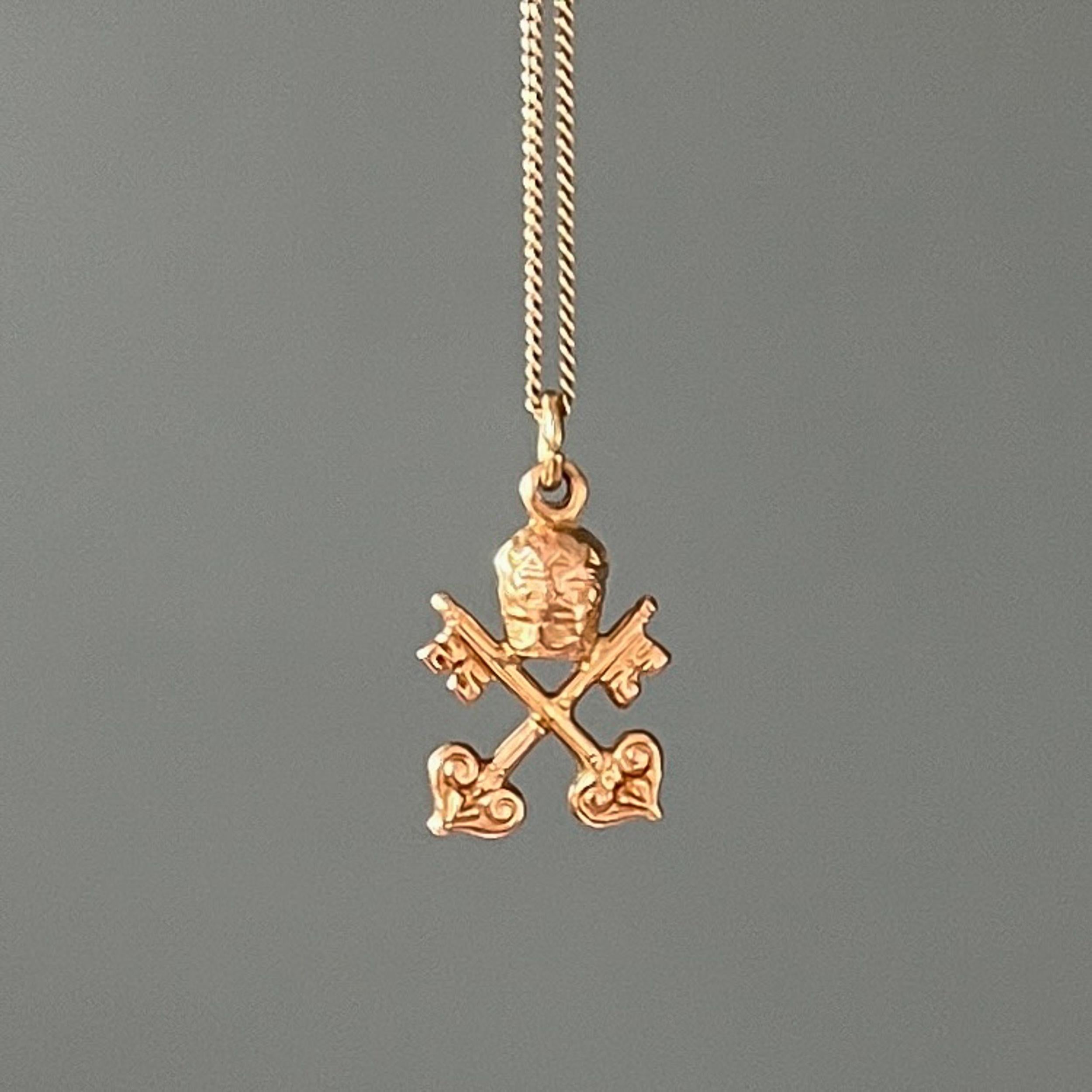 A vintage 18 karat yellow gold keys of the kingdom of heaven charm pendant. The charm with two keys represents the power of loosing and binding. The triple crown - the tiara - symbolizes the triple power of the Pope as 