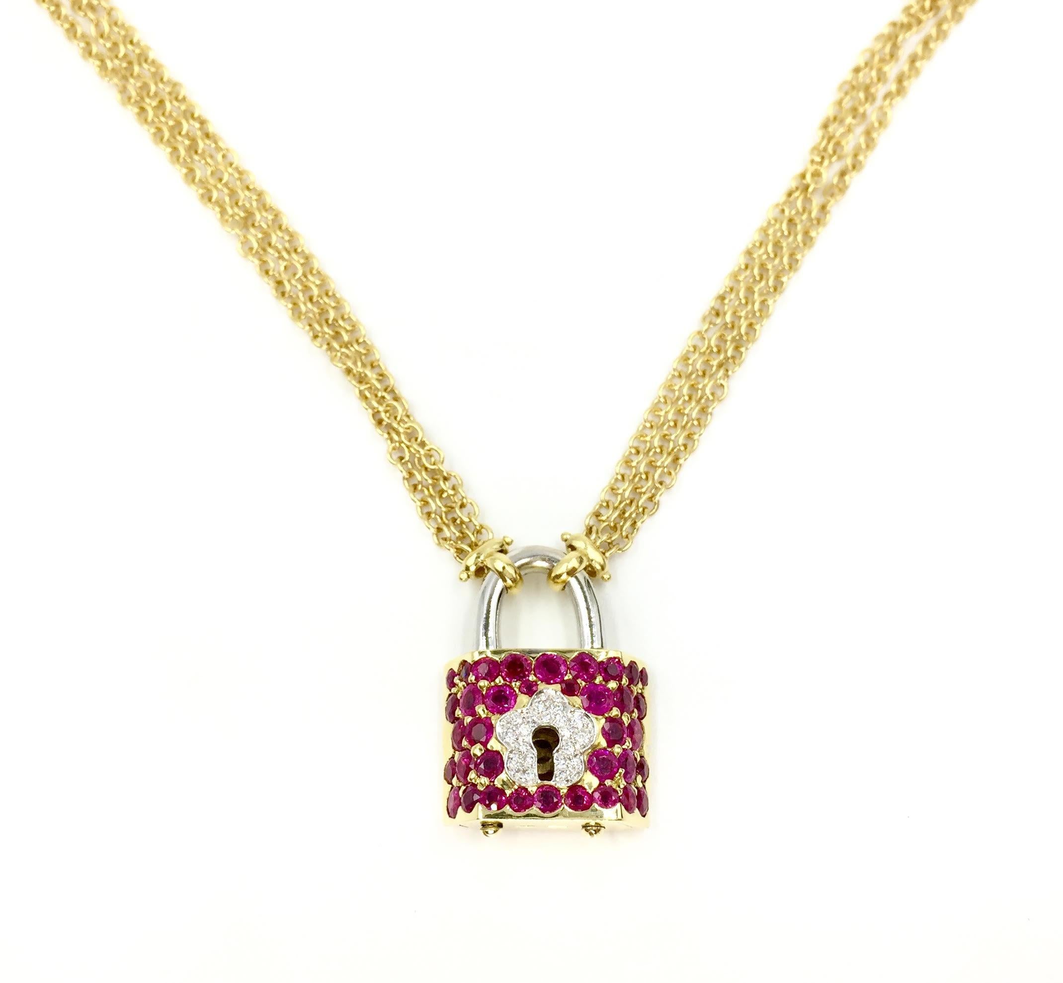 Circa 1990, this high quality ruby and diamond encrusted two tone padlock pendant actually opens and closes with the 18k yellow gold key. The necklace can be worn with or without the dangling petite key. 34 gorgeous round rubies have an approximate