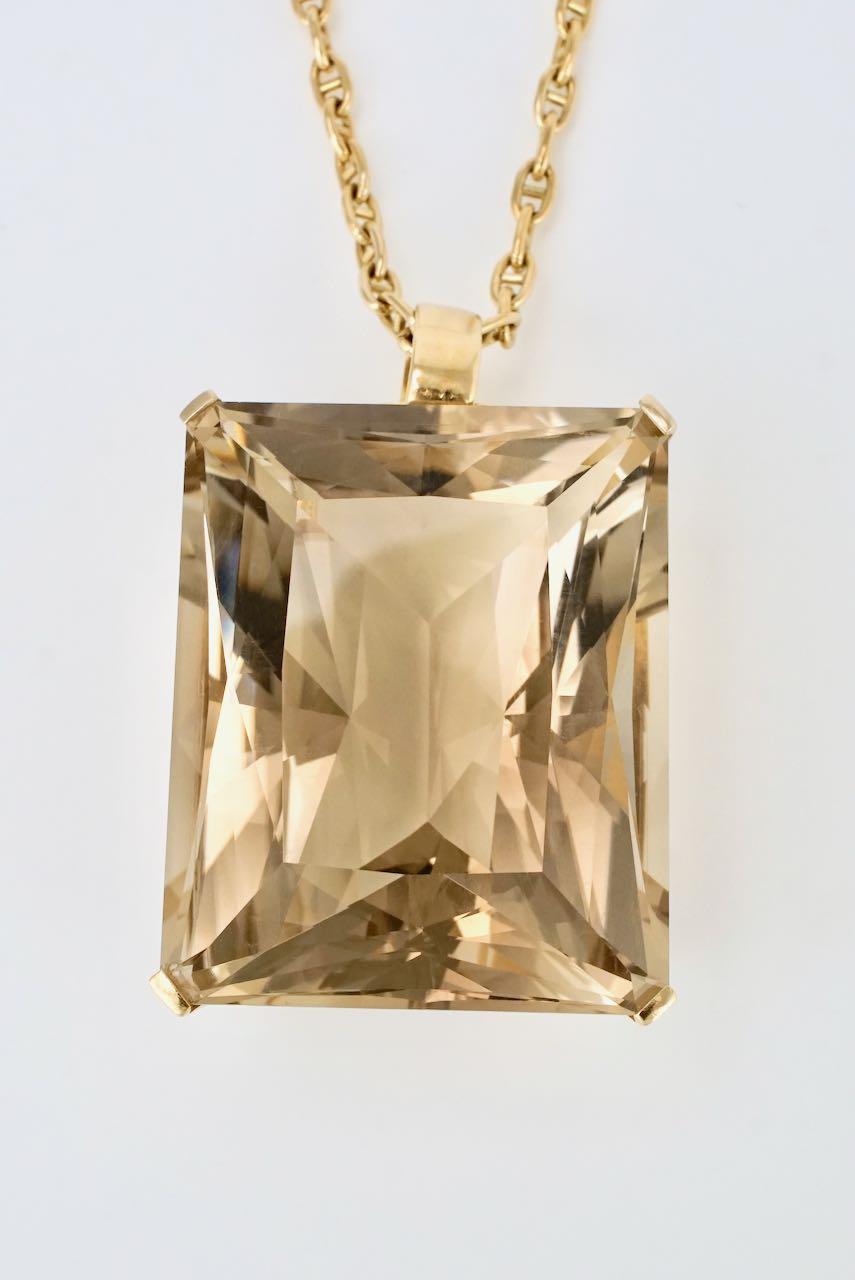 A vintage 18k yellow gold rectangular citrine pendant and chain featuring a bold rectangular scissor cut smoky citrine of a pale golden colour of approx 130cts four claw set in a plain frame suspended on an 18k oval mariner link chain necklace with