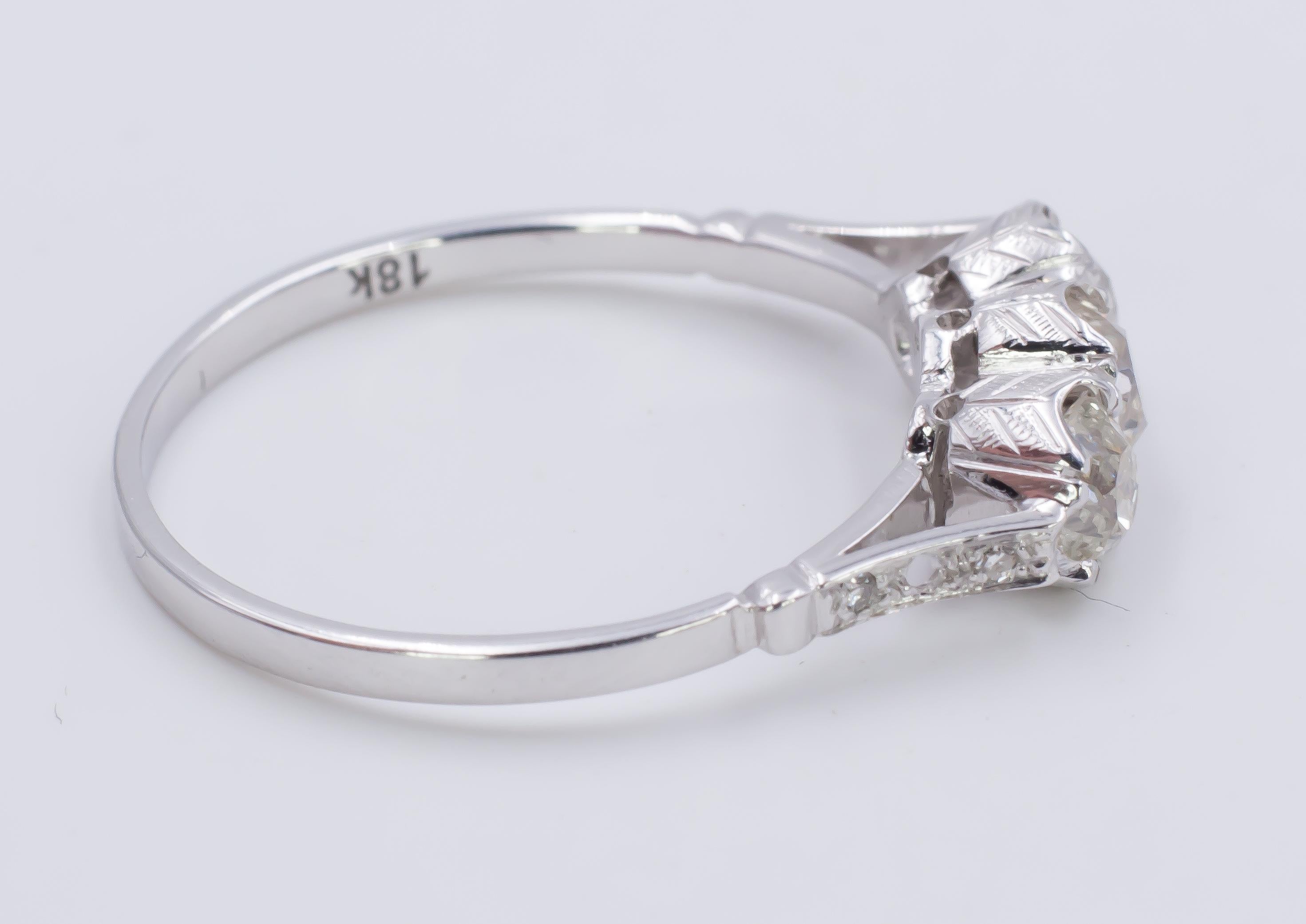 This stunning trilogy ring is crafted in 18K white gold throughout, and is set with three old mine cut diamonds, totalling 1.09ct. The shoulders are decorated as well with diamonds, while the gallery claw shows a beautiful carved setting. 
The ring