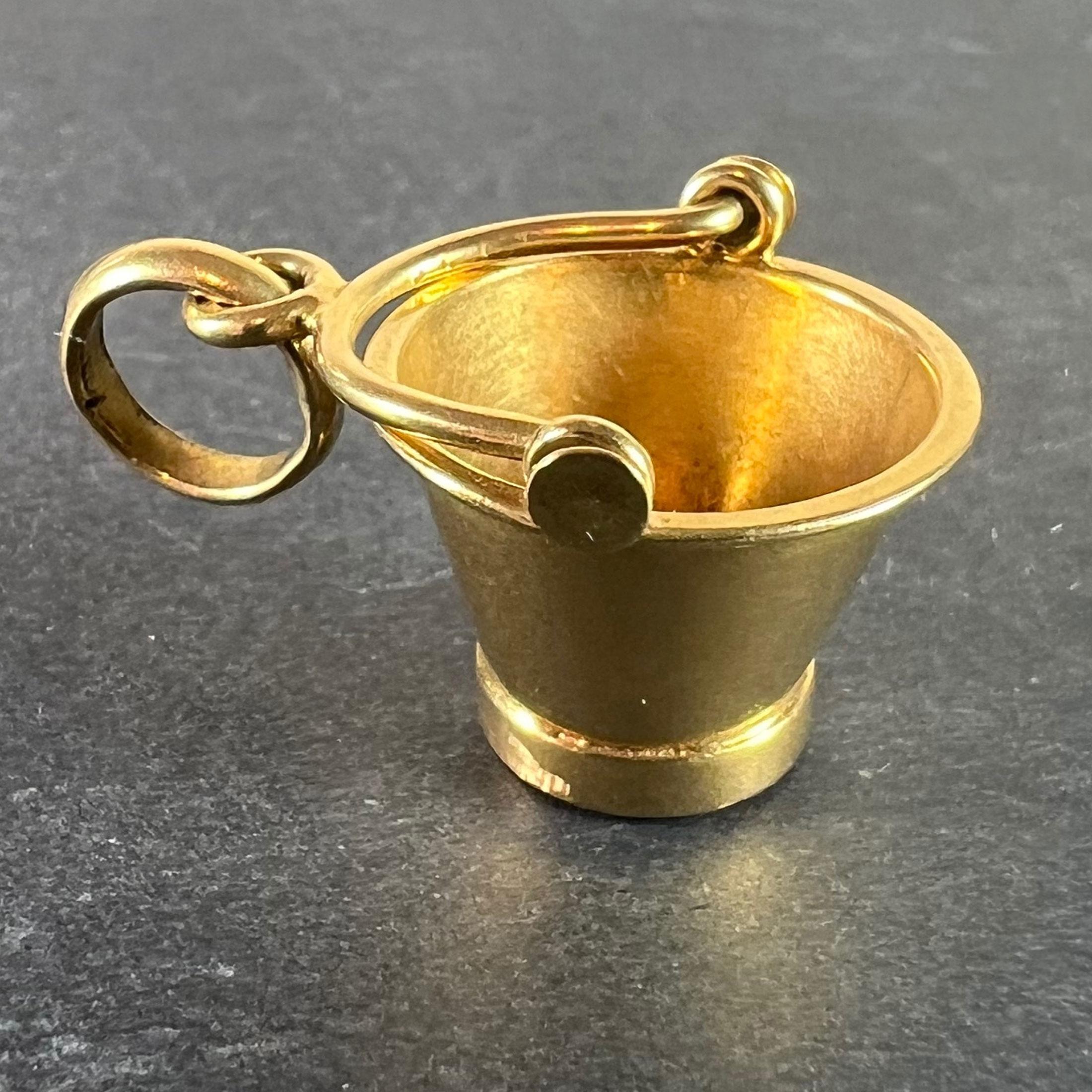 A vintage 18 karat (18K) yellow gold charm pendant designed as a champagne bucket. Stamped with the owl mark for French import and 18 karat gold, along with 750 for 18 karat gold and an unknown maker's mark to the jump ring.

Dimensions: 2.2 x 1.6 x