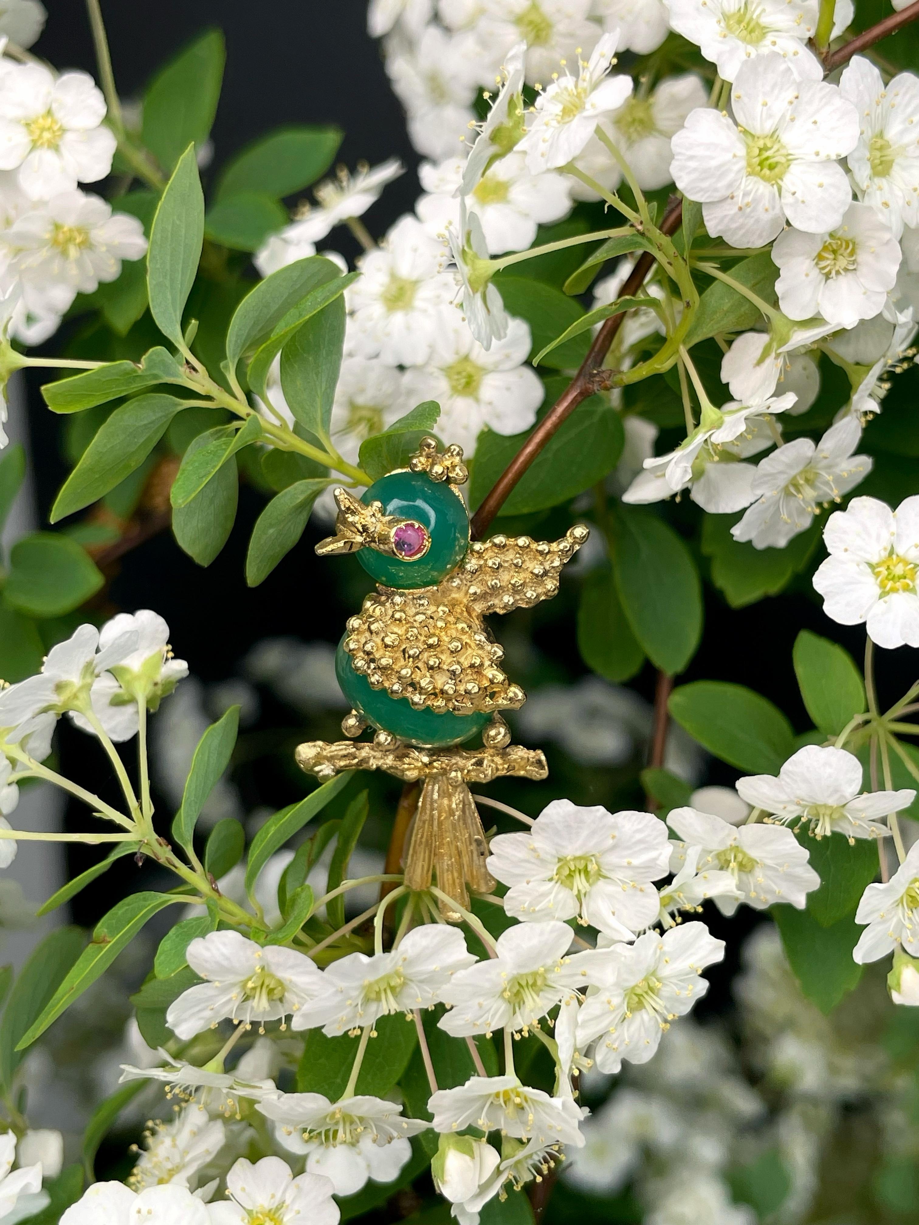 This is a vintage small bird pin brooch crafted in 18K yellow gold. Circa 1970.

It features two cabochon cut green chalcedonies and one round cut ruby. 

Has a safe clasp. 

Weight: 4.51g
Size: 3x1.5cm

IMPORTANT: As a buyer, you are fully