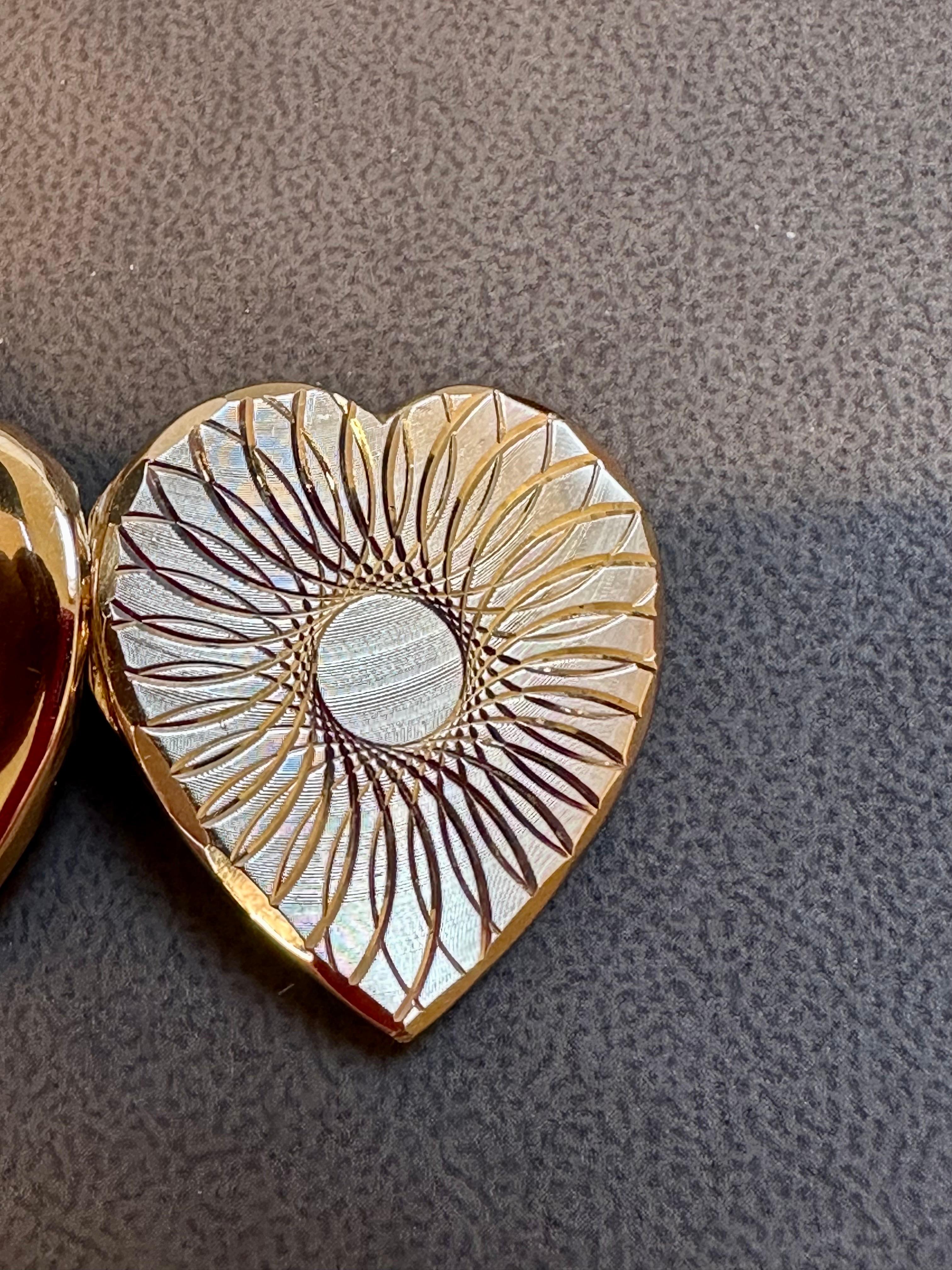 This vintage heart locket is a beautiful piece of jewelry crafted from 18 karat yellow gold. The locket has space for two pictures or can be used to hold medicine, making it both functional and stylish. The locket is 1.2 inches wide and 1.3 inches