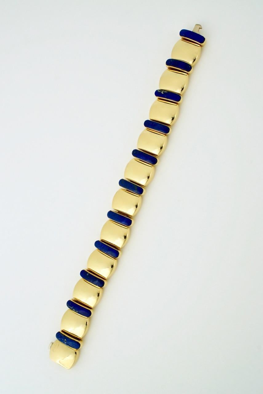 A vintage bracelet of 11 puffy pillow shaped panels of 18k yellow gold interspersed with long lozenge shaped cabochons of deep blue Lapis Lazuli bezel set and finished with an integrated push clasp: the tongue and button of which is in white gold  -