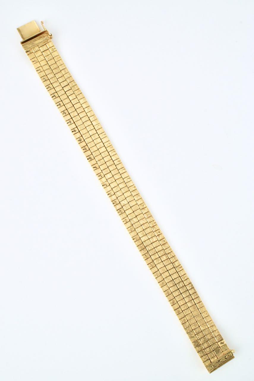 An 18k yellow gold bracelet comprised of 4 strands of omega style chain with tile like squares to the surface with an all over Florentine finish and each alternate tile engraved with a bright cut motif and finished with an integrated box clasp