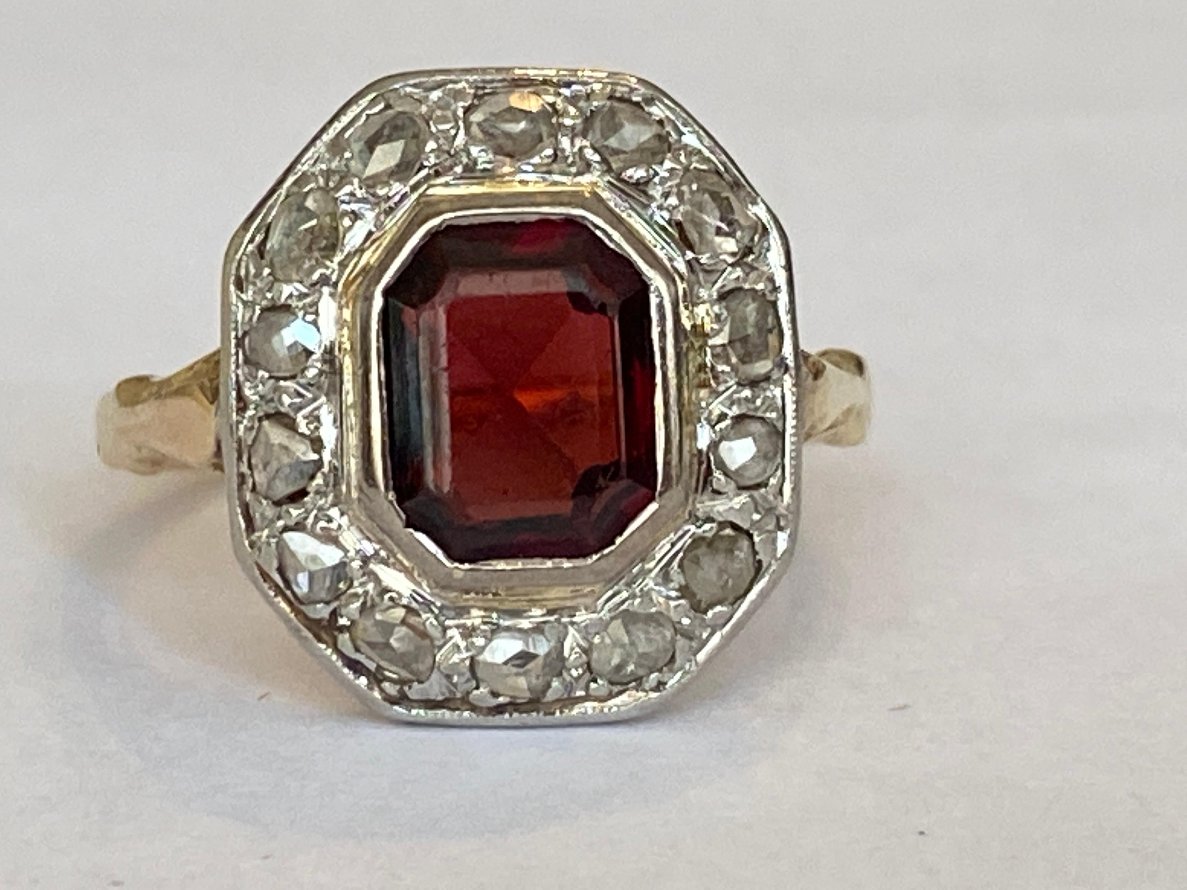 Beautiful 18 carat gold vintage  ring set with an emerald cut garnet of approximately 2.00 crt and surrounded by an entourage of rose cut diamonds of approximately 0.60 crt. The stone has signs of wear.
Grade: 18KT (approved 750)
Weight: 4