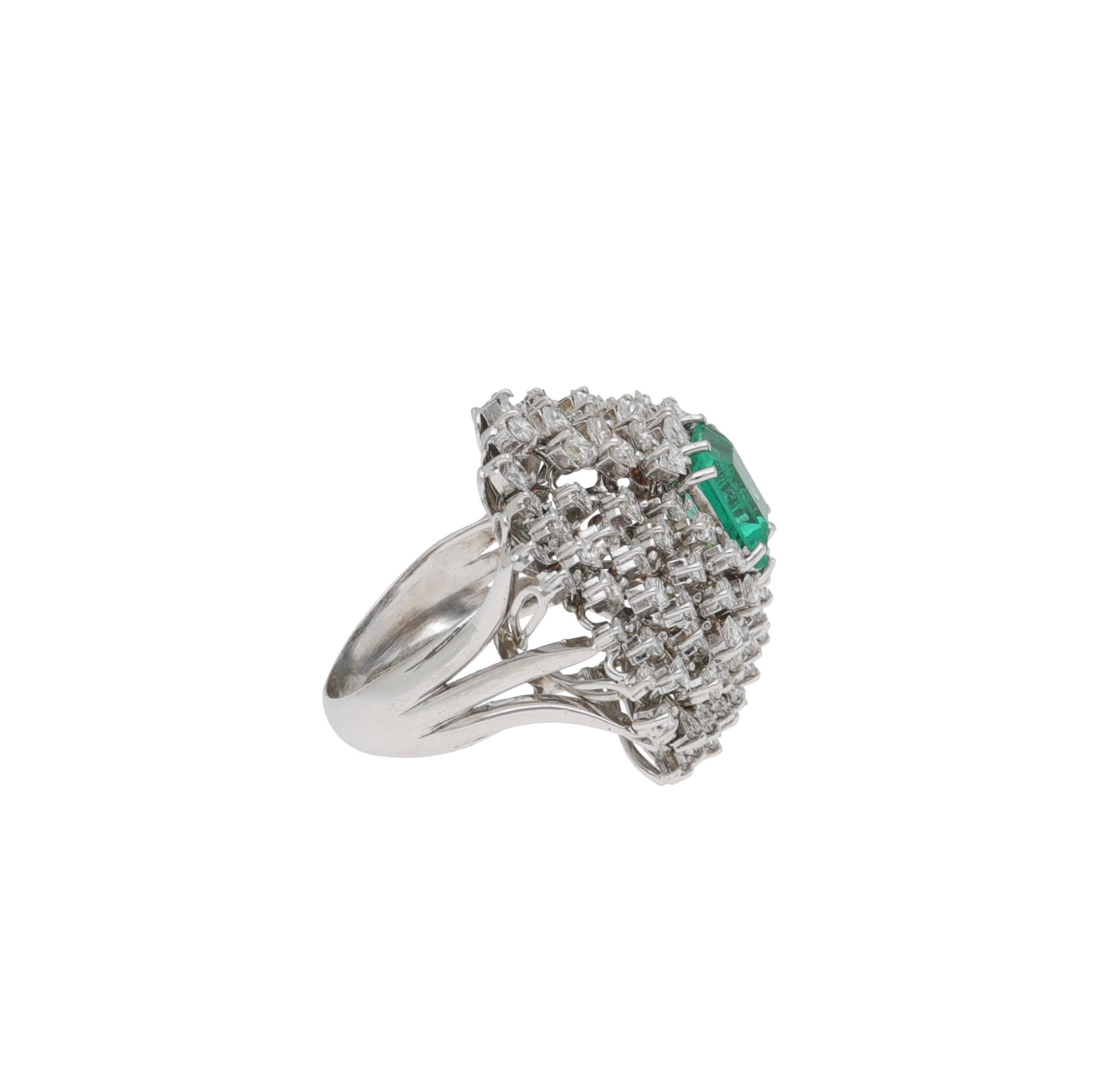 Anillo de oro blanco de 18 kt. con diamantes y esmeralda.
Los diamantes están engastados en distintos niveles, creando una geometría tridimensional.
La esmeralda está engastada en el centro del anillo, rodeada por la luz de los diamantes.

Diamantes