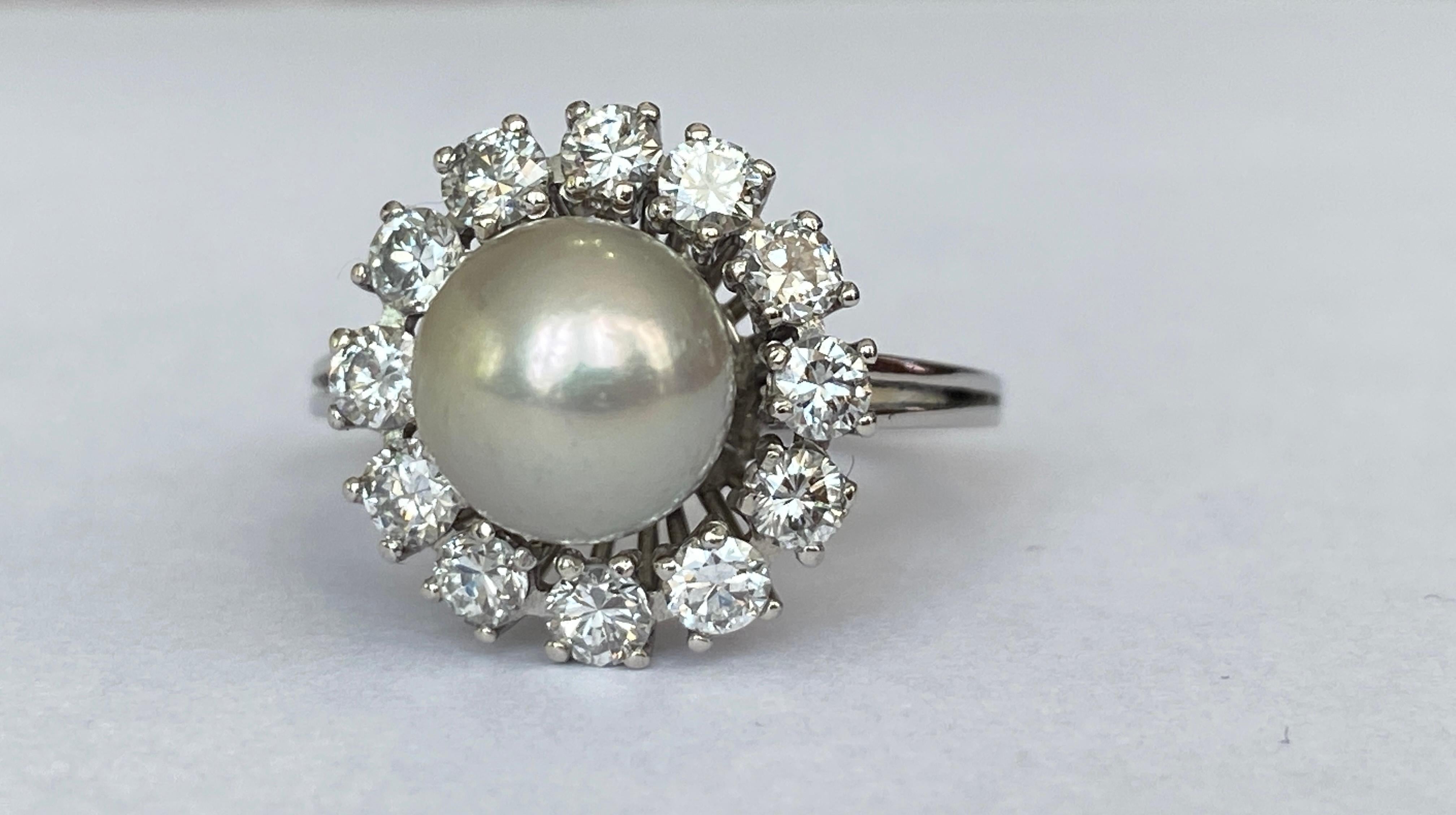 Angebotener Vintage-Ring aus 18 Karat Weißgold mit Rosette, verziert mit 1 weiß-grauen Süßwasserperle von ca. 8,65 mm und umgeben von 12 Brillanten im alten europäischen Schliff  Diamanten von insgesamt ca. 1,10 ct der Qualität G/VS/SI.

Goldgehalt: