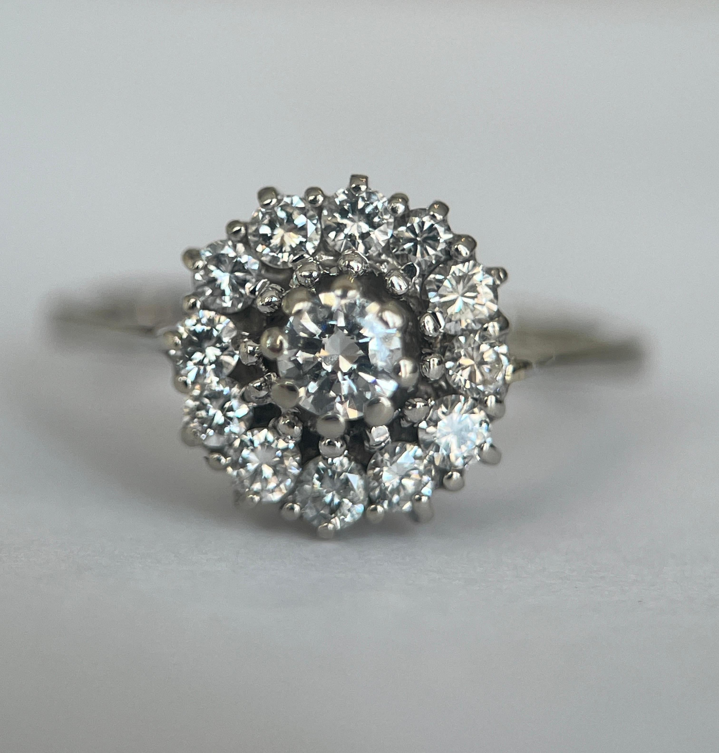 Elegante e senza tempo, questo anello di fidanzamento vintage in oro bianco 18 kt a rosetta è una vera incarnazione della raffinatezza classica. Disegnato con una delicata montatura a rosetta di ispirazione floreale, l'anello presenta un totale di