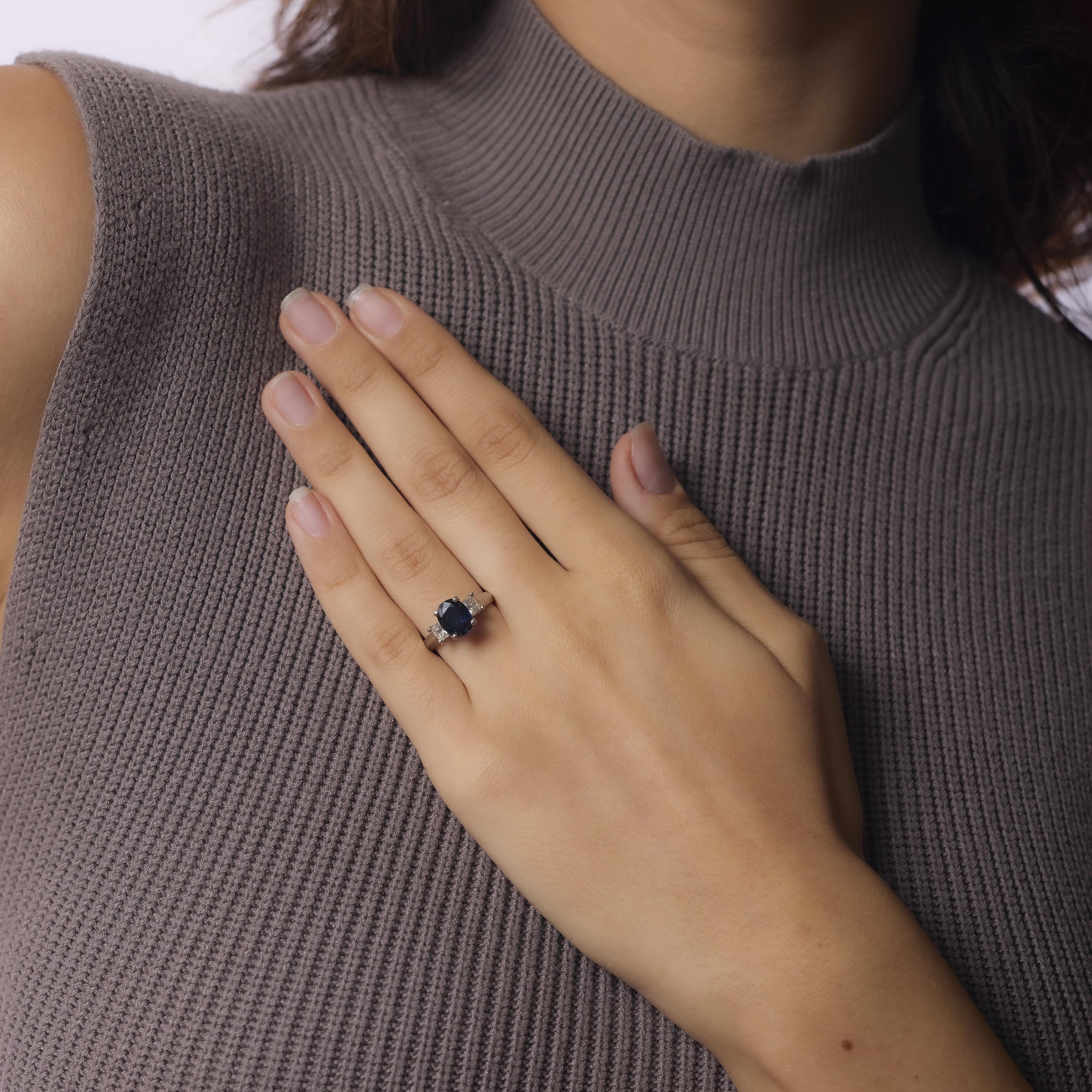 This vintage 18k white gold ring centers a richly hued 1.80 carat oval sapphire, flanked by four striking G-color princess cut diamonds totaling 1 carat. Crafted in the 1980s and hallmarked PLD, its bold lines and brilliant contrast evoke timeless