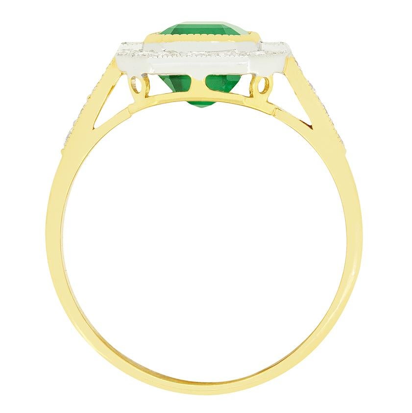 Dieser schöne Smaragdcluster stammt aus den 1970er Jahren. Der natürliche Smaragd im klassischen Smaragdschliff wiegt 1,85 Karat und ist in 18 Karat Gelbgold gefasst. Ein Baguetteschliff-Diamant flankiert den zentralen Stein, der von einem Halo aus