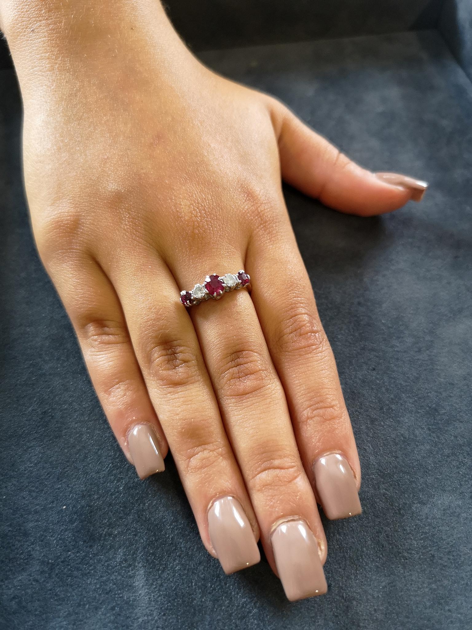 A traditional platinum claw mount set with a fire-red central oval-cut ruby of approximately 0.60 of a carat, flanked by two brilliant-cut diamonds of approximately 0.20 of carat each, H-I colour, SI clarity. Two further rubies of approximately 0.15