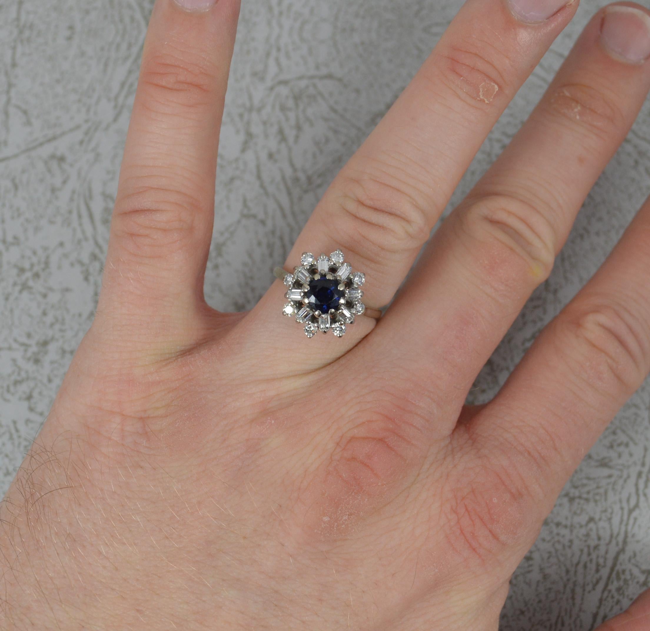 A beautiful Sapphire and Diamond ring.
Solid 18 carat white gold example.
Designed with a round cut dark blue sapphire to centre, 6mm diameter.
Surrounding are eight emerald cut diamonds surrounding with a final border of a further eight round
