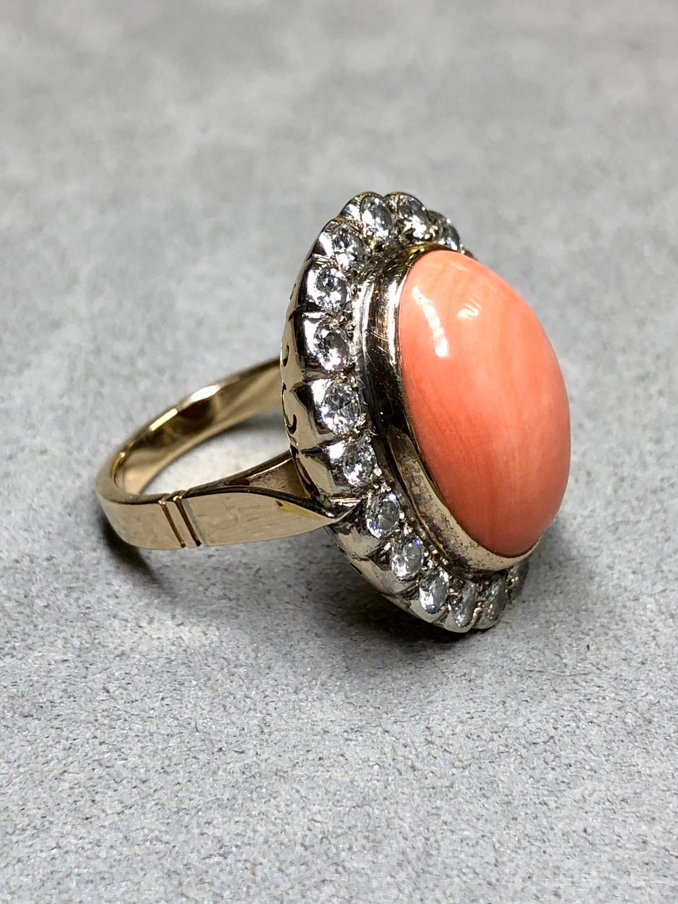 A bold Rosetta style cocktail ring c. the 1950’s done in 18K yellow gold with silver top centered by a large natural pink coral cabochon surrounded by approximately 2ctw in H-I color Vs1-2 clarity transitional cut