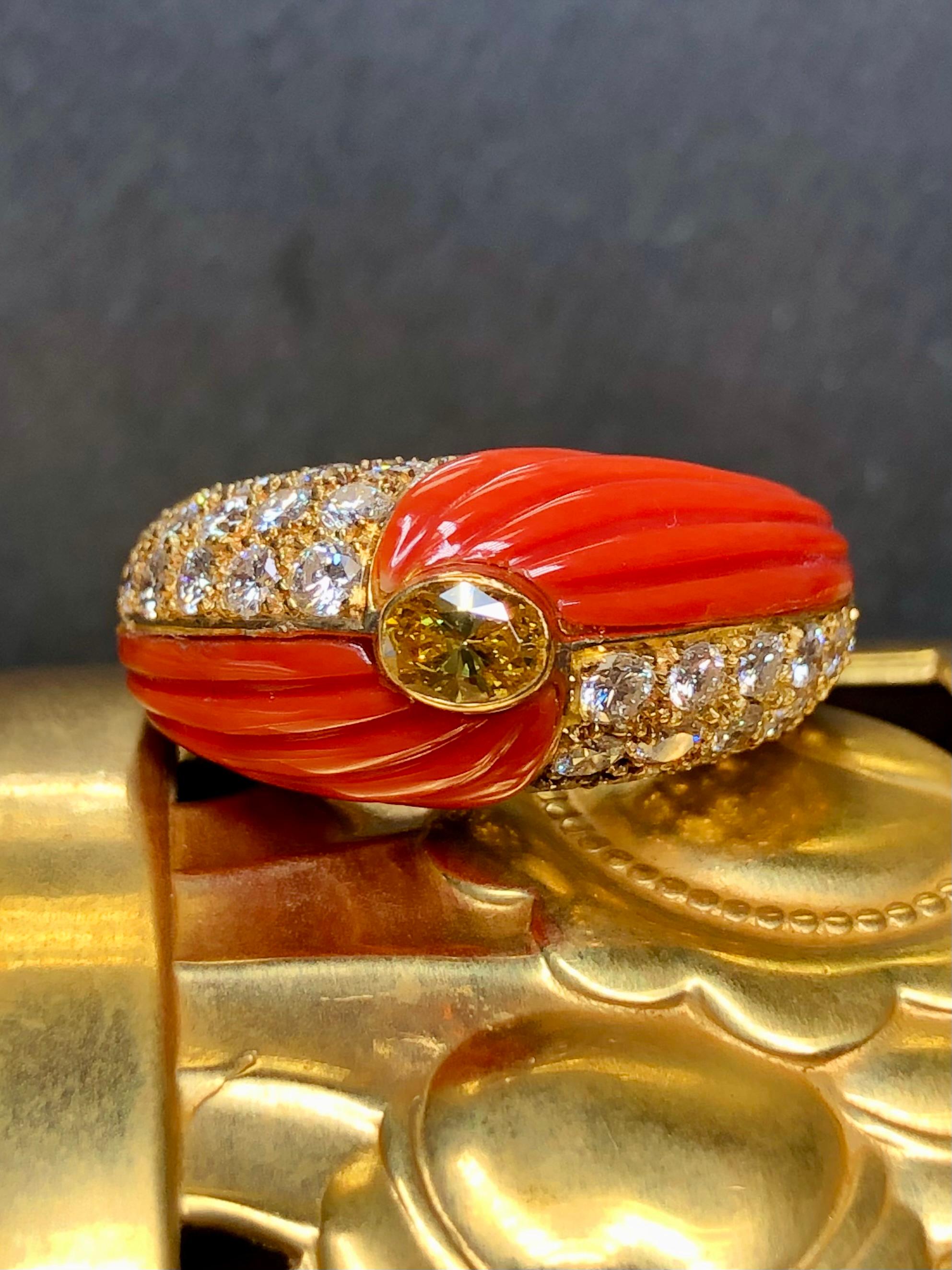 This ring is GORGEOUS! We are definitely partial to this one for obvious reasons. It is done in 18K yellow gold and inlaid with gorgeous, bright carved coral on both sides and set with approximately 1.70cttw in G-H color Vs1-2 clarity round diamonds
