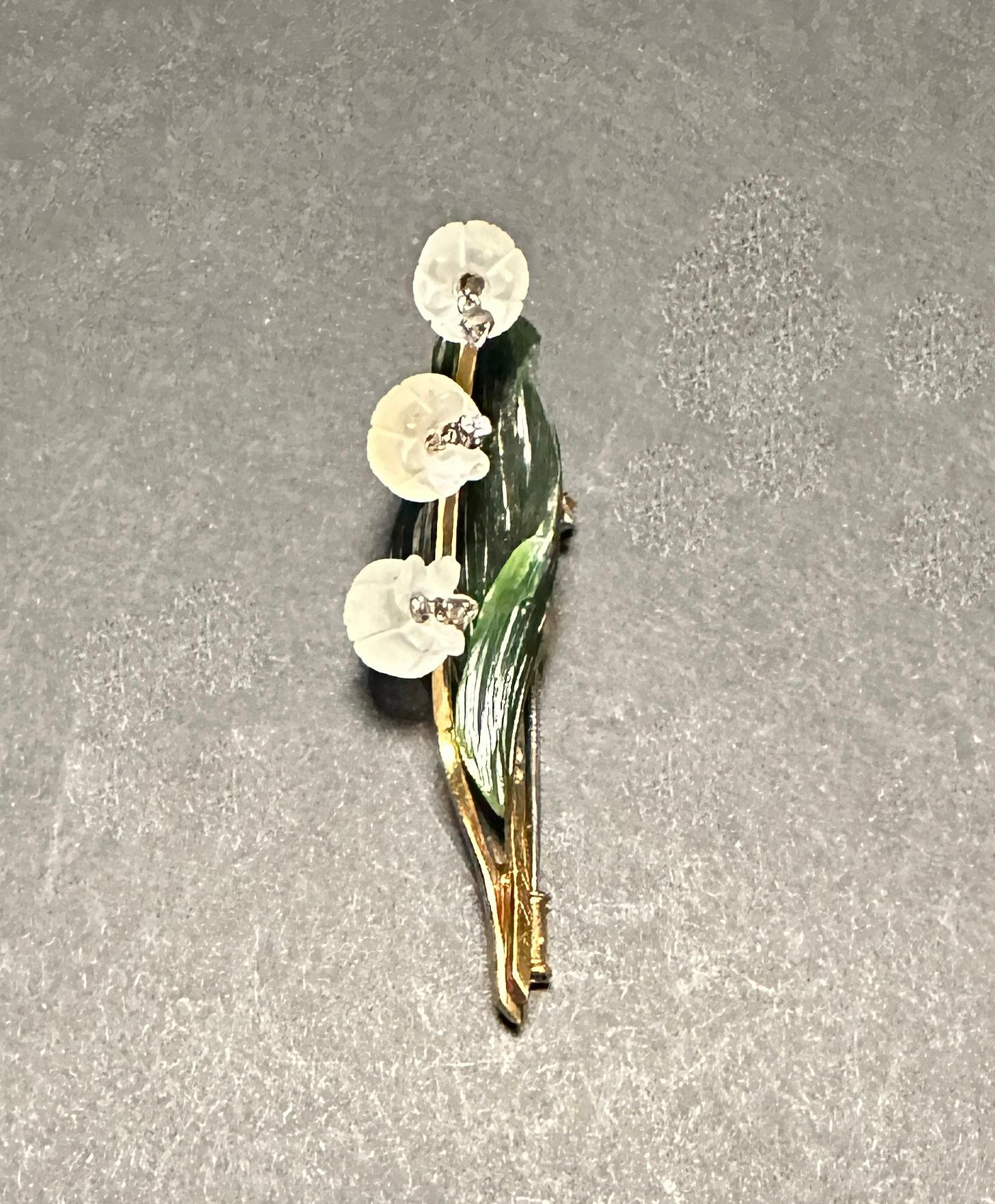 A lovely 18K yellow gold vintage floral brooch realistically modeled as lily of the valley, set with frosted carved rock crystal flowers, each suspending a sparkling full round cut diamond, mounted on an 18k yellow gold stem and a carved jade  leaf.
