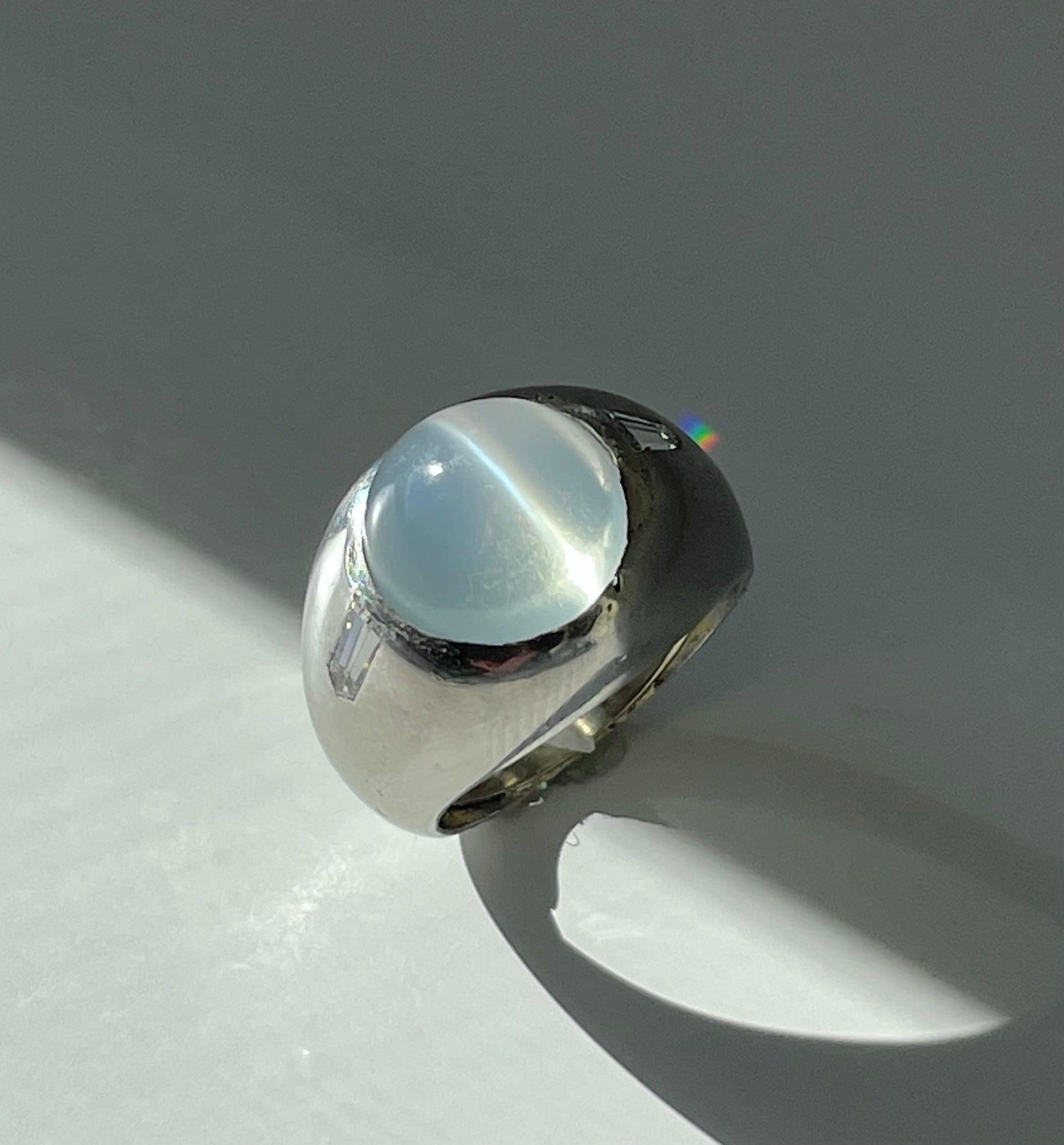 Weight: 24.7

Size: 7.25

Diamonds: two .16 carat bullet shaped diamonds, VS 2 clarity H-I range in color

Metal: 18k white gold

Cat's Eye Moonstone: 12mm

Measurements: 15.5mm north to south

Notes: a piece of white gold has been laid inside the