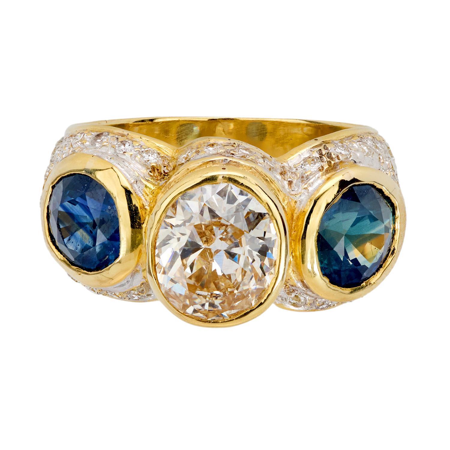 A marvelous diamond and sapphire statement ring from the Vintage (ca1960s) era! Crafted in vibrant 18k yellow gold, this ring features a central antique oval cut diamond, which has an approximate carat weight of 1.86ct. The bezel-set stone displays