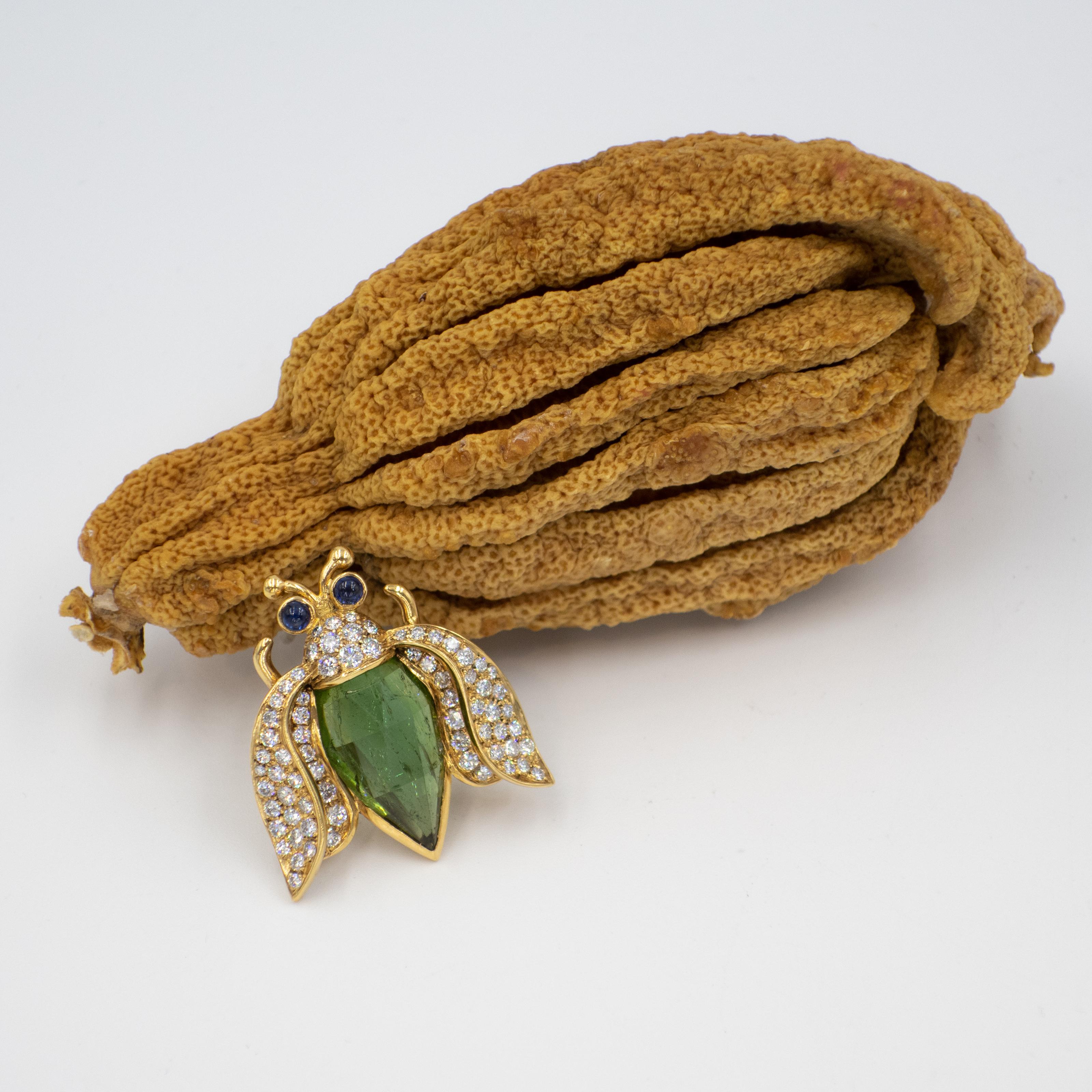 1990s 18K yellow gold diamond tourmaline Beetle fur clip brooch. Beetle boasts diamond encrusted wings. 72 Brilliant cut diamonds approximate 3.00 carats are in G-H color VS clarity, facet cut green tourmaline body and cabochon sapphire eyes.
18K