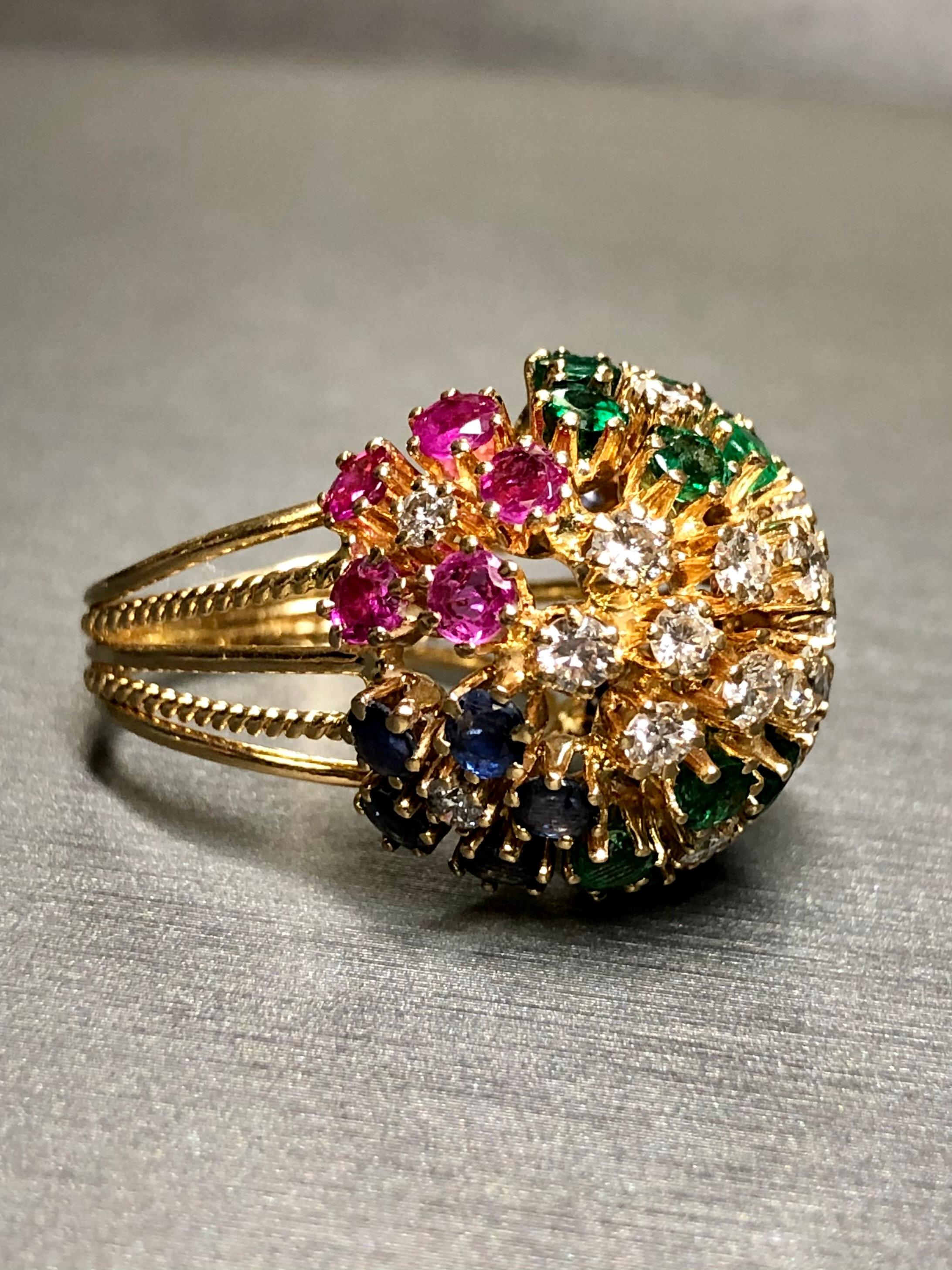 
 A classic vintage bombè cocktail ring crafted in 18K yellow gold set with approximately 1cttw in H-J color Vs1-Si1 clarity round diamonds, 1cttw in natural emeralds, 1.50cttw in natural sapphires and 1.50cttw in natural rubies. A classic vintage