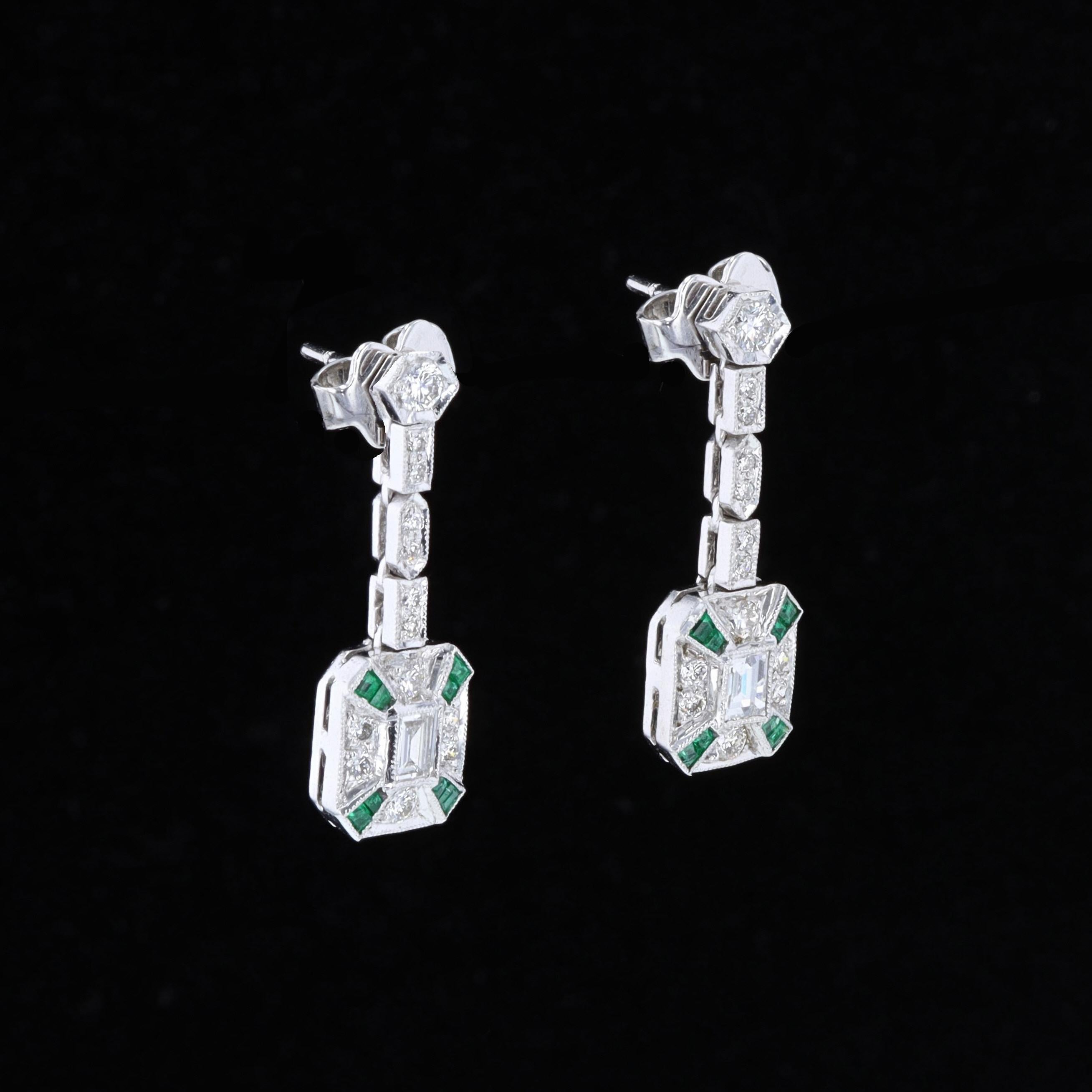 Exquisite workmanship combines elegance and opulence in this pair of vintage emerald and diamond earrings. The 18K white gold earrings feature round and emerald cut diamonds and emeralds and measure 27mm by 9mm. The earrings weigh 7.2 grams.

