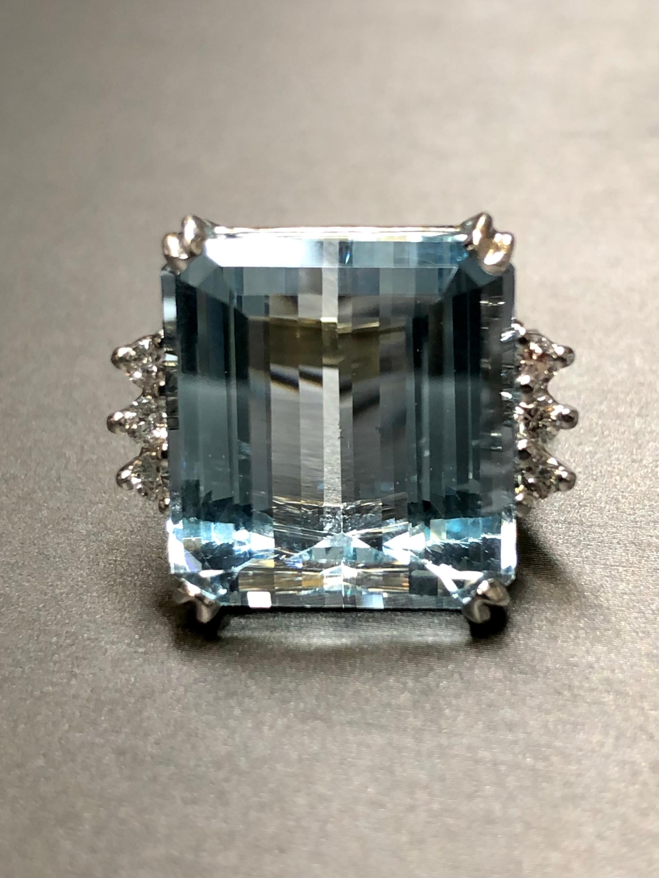 A stunning vintage cocktail ring done in 18K white gold and centered by an approximately 20ct natural deep blue aquamarine (17.55mm x 16.18mm x 10.45mm) of gorgeous cut quality and proportions; a very lively stone. Flanking the center stone is