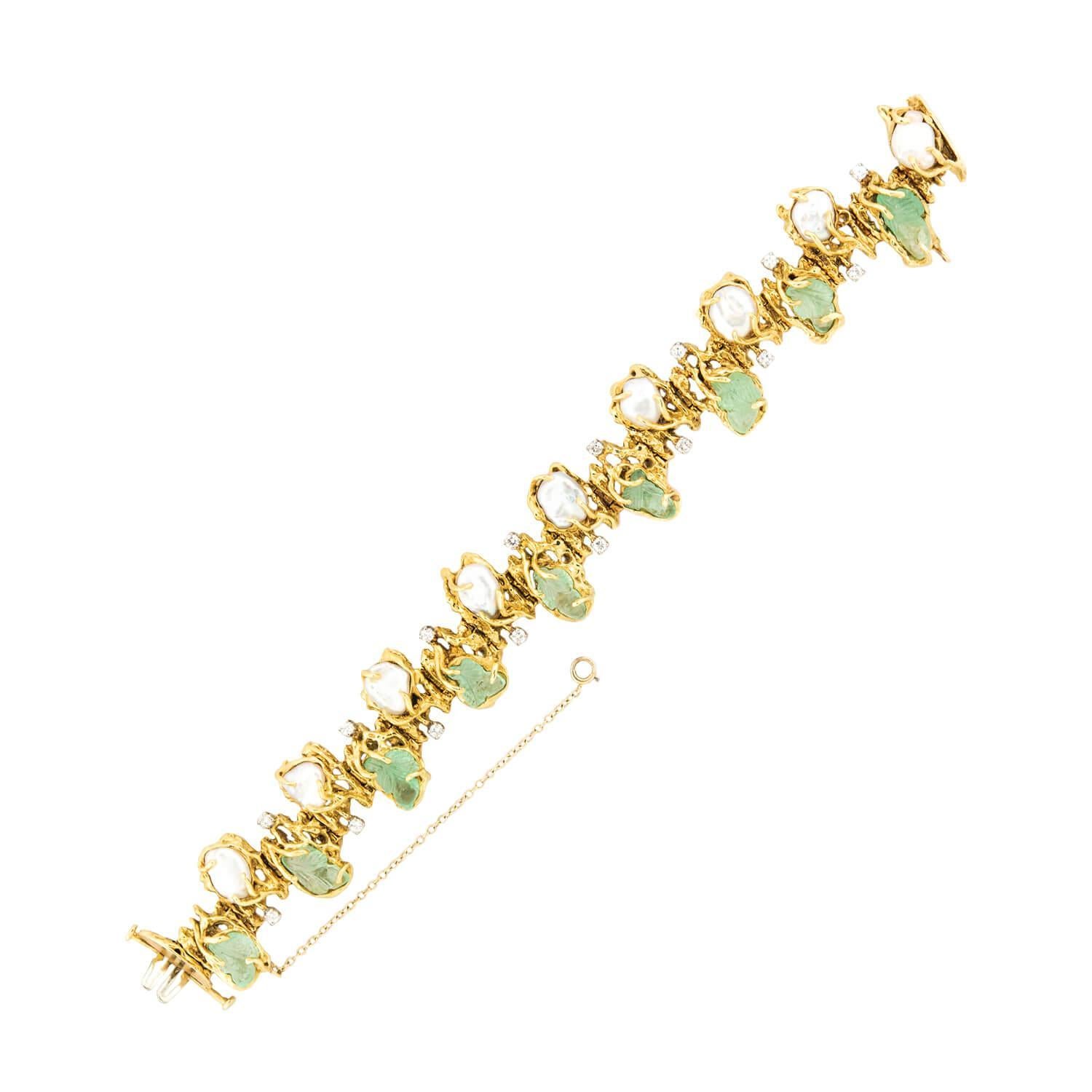 A gorgeous emerald, pearl, and diamond bracelet from the Vintage (ca1960s) era! Crafted in 18k yellow gold, the piece features nine carved emerald stones, which are held within three-prong settings, which resemble tree branches. The piece also