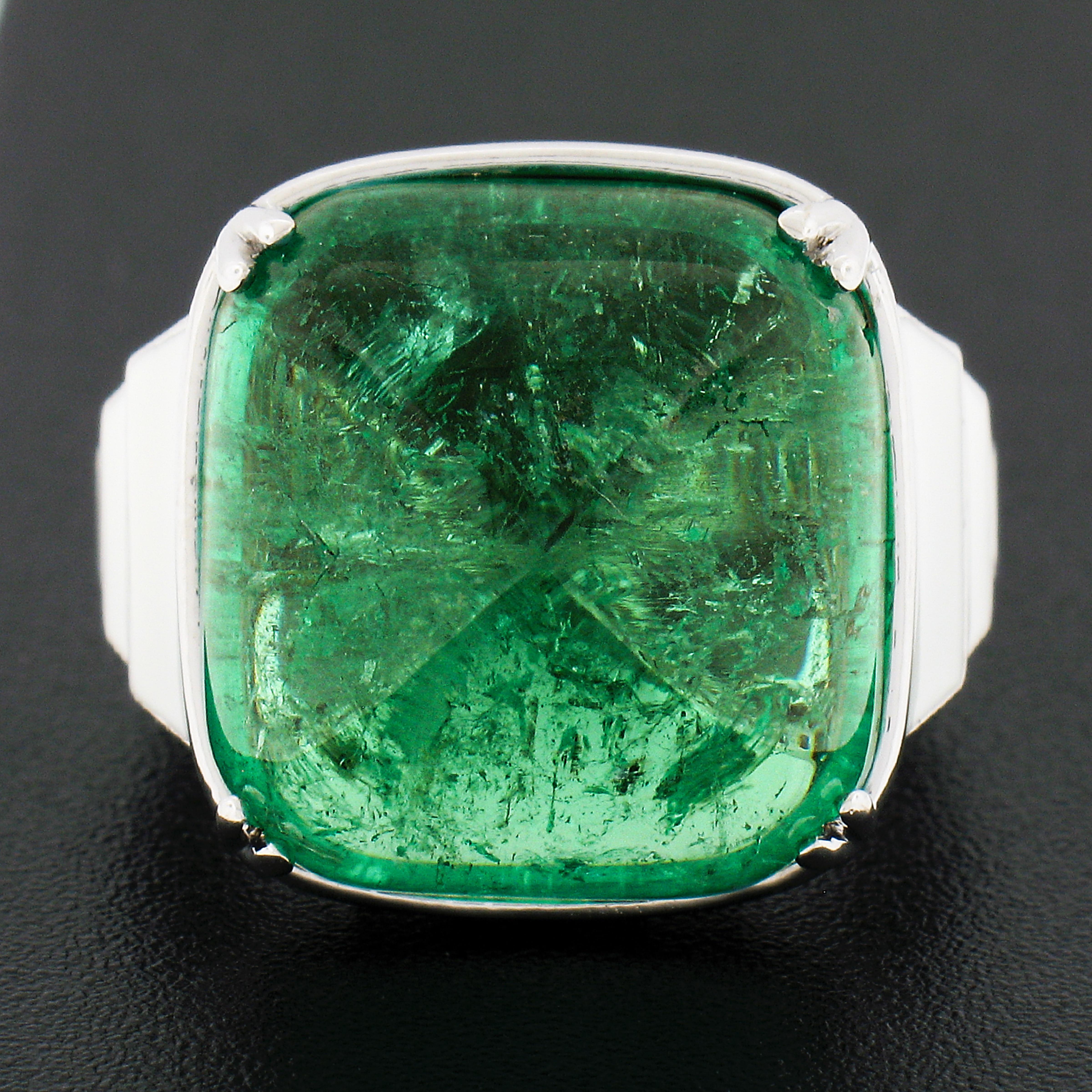 Here we have a gorgeous and uniquely designed cocktail ring that is crafted in solid 18k white gold. It features a large cushion sugarloaf cabochon cut natural emerald stone that is dual prong at its center. This approximaltey 23 carat, GIA