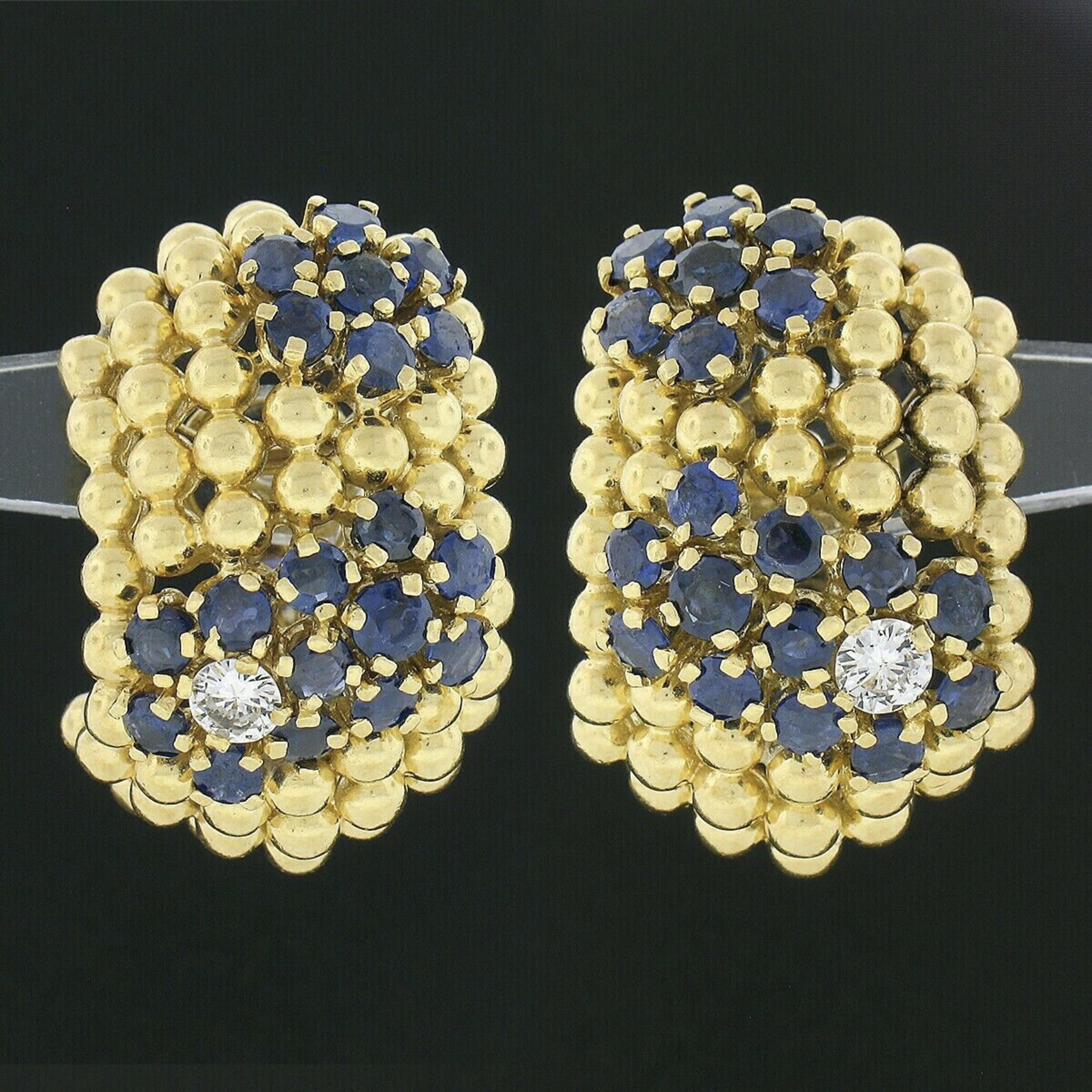 This outstanding pair of vintage earrings is crafted in solid 18k yellow gold and features a wide cuff design with each adorned with 3 sapphire and diamond flower accents throughout. The wide design is constructed from 7 rows of gold beads in which
