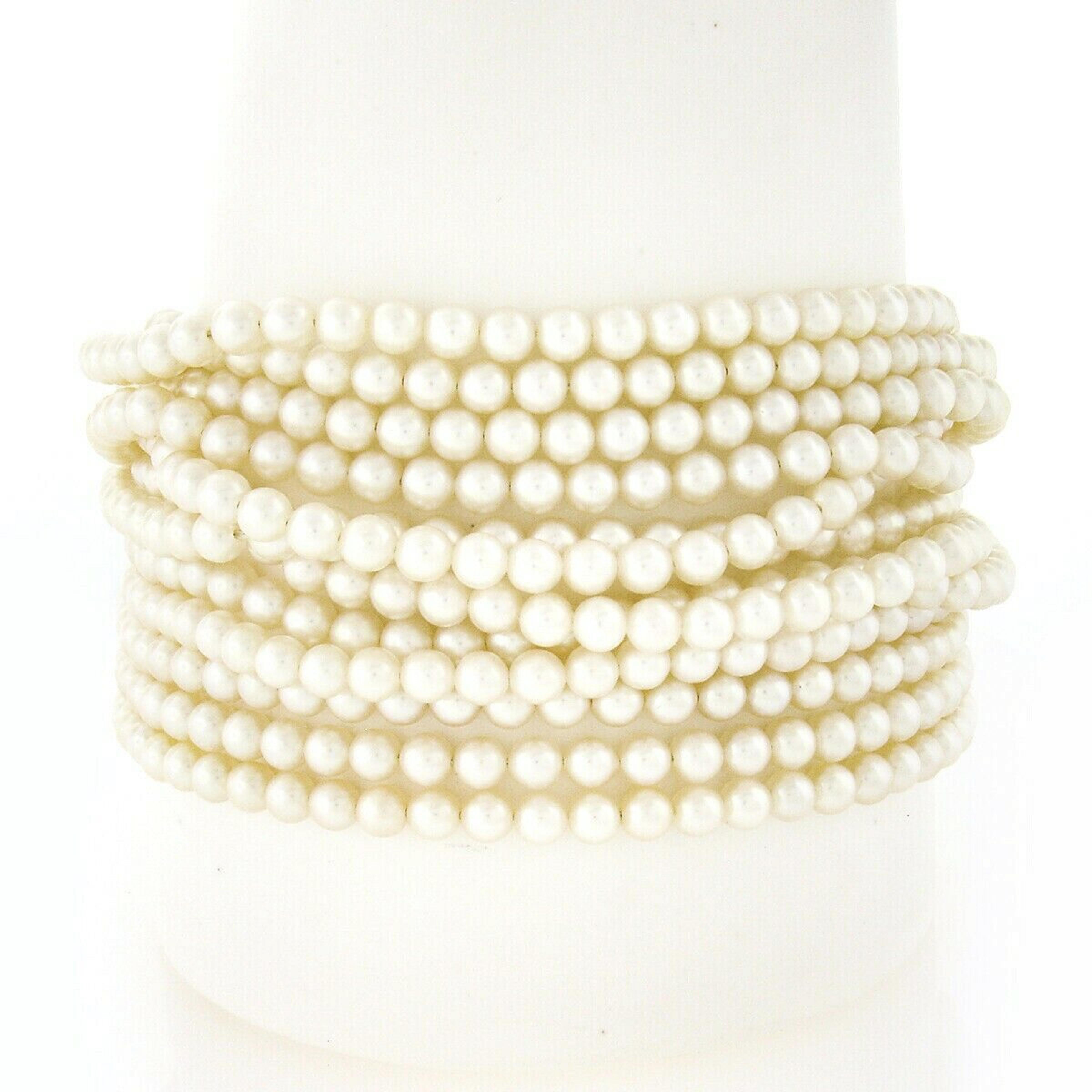 This magnificent vintage bracelet features 12 strands of round cultured pearls with a large textured clasp crafted from solid 18k yellow gold. The very fine quality pearls are well matched in size and nice white color, and are absolutely gorgeous