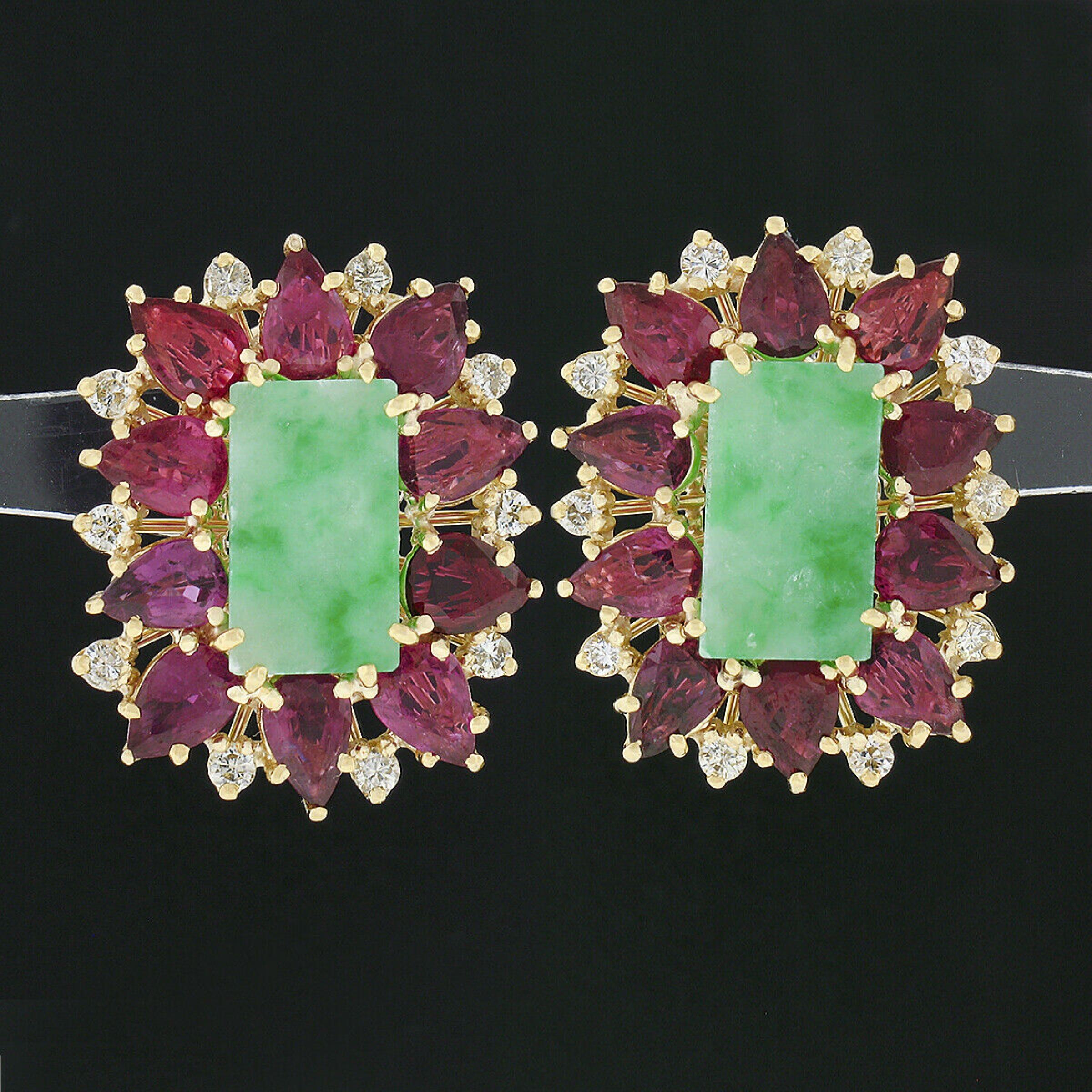 This breath-taking pair of vintage statement earrings is crafted in solid 18k yellow gold with each featuring a fine jade stone neatly set at their center surrounded by and absolutely stunning halo of rubies and diamonds throughout. The beautiful