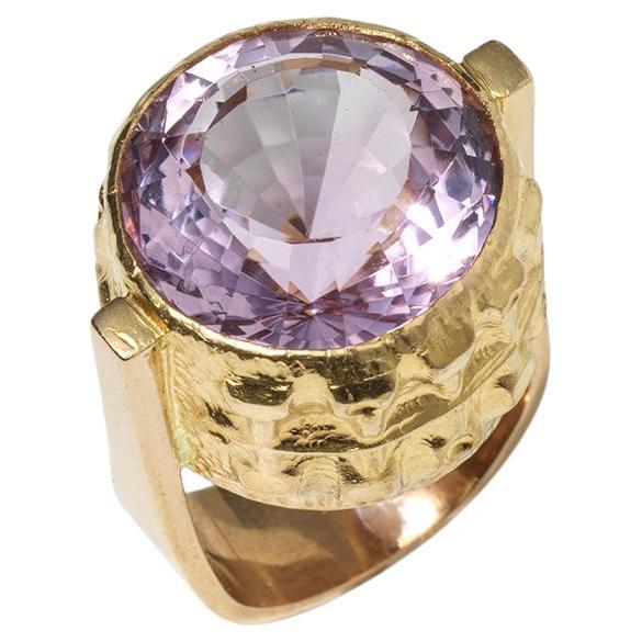 This 18 karat gold ring from 1969 is crowned with a striking amethyst, exuding classic cocktail ring grandeur. The stone's purple hue is captivating, set within a beautifully patterned mount that catches the light. The band's form is solid, with an